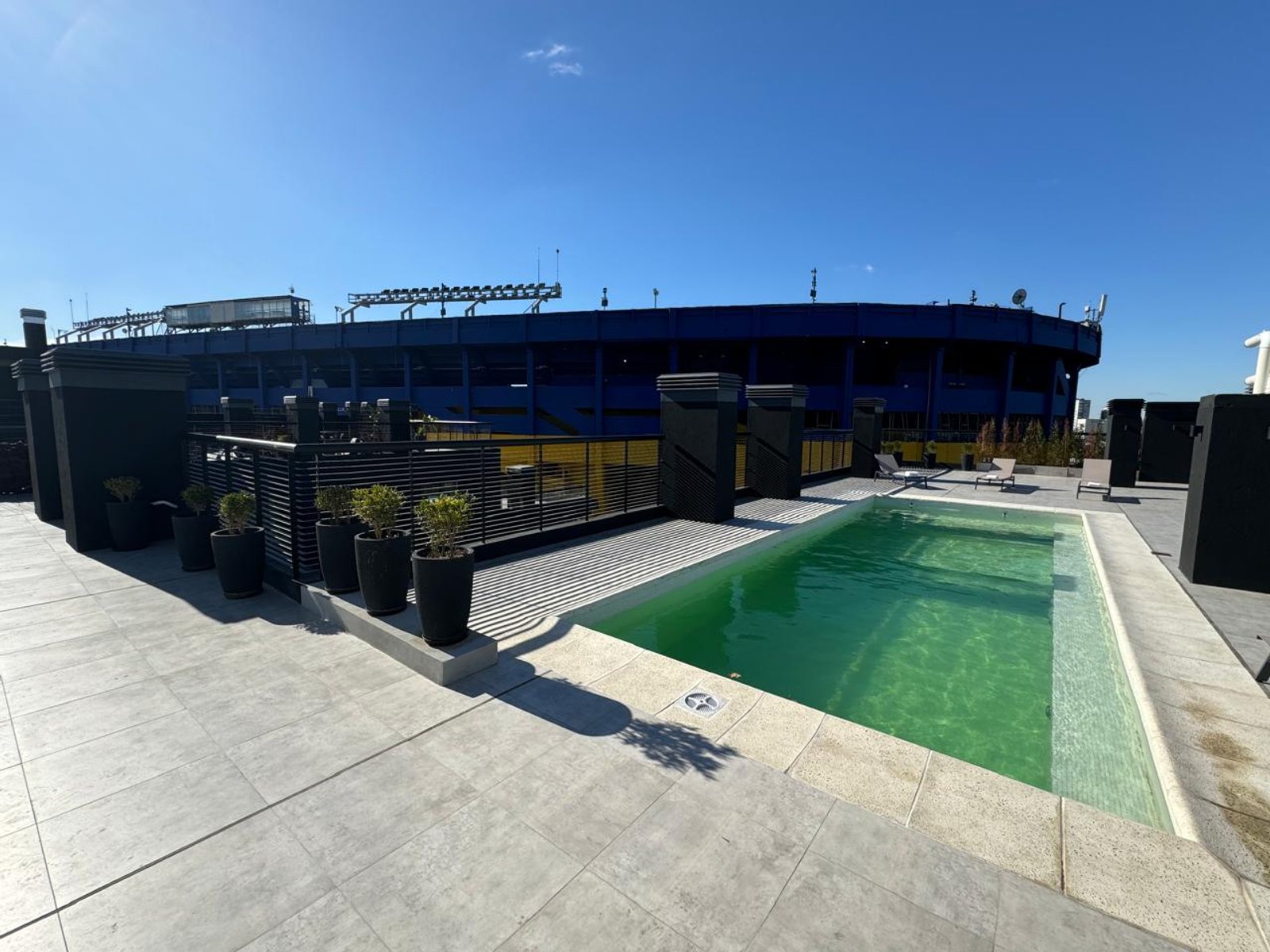 Terraza de piscina en azotea con vista a estadio — proyecto UNDICI - Howard Johnson- La Boca, por COMOTTO - SOMMER  - ARQUITECTOS, en Brandsen 927