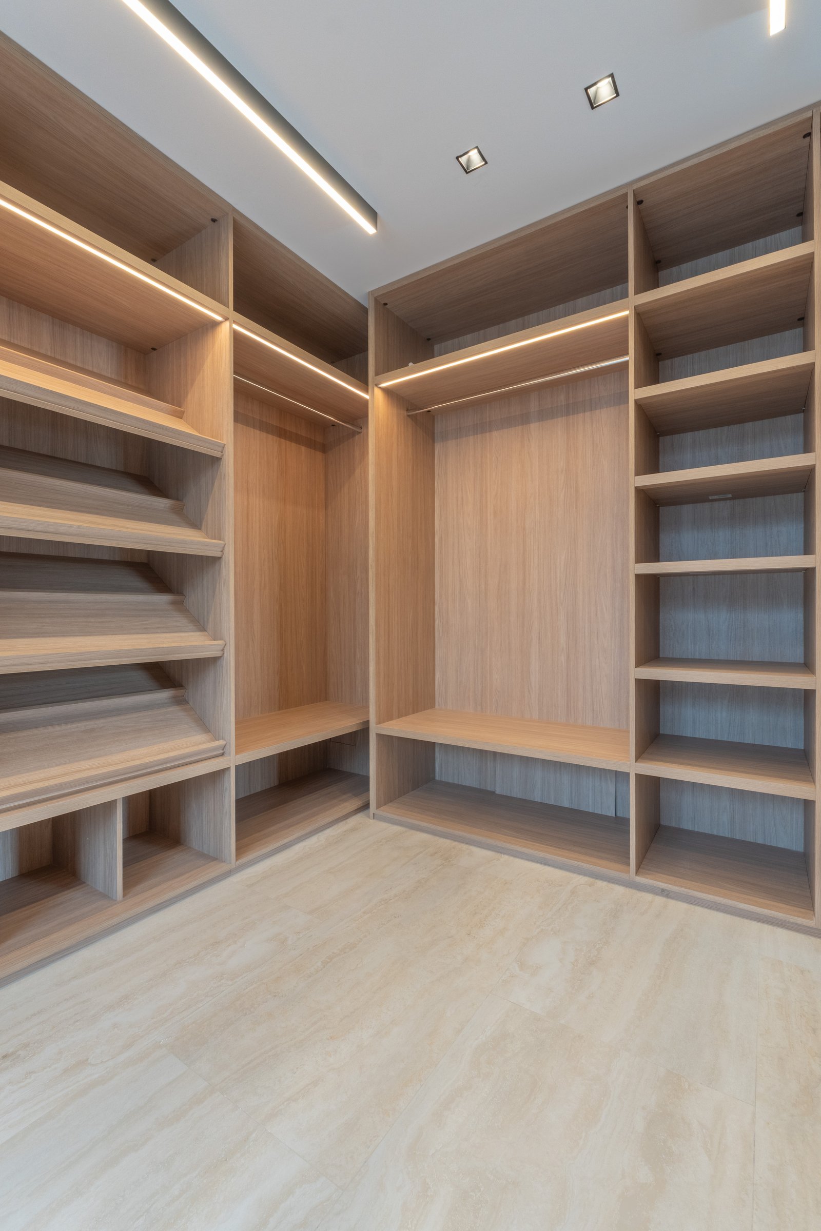 Closet moderno amplo com armários de madeira clara e iluminação indireta — projeto Yacht - Estudio CCWay, por ABEJA CONCEPT, em Av. de la Ribera 560
