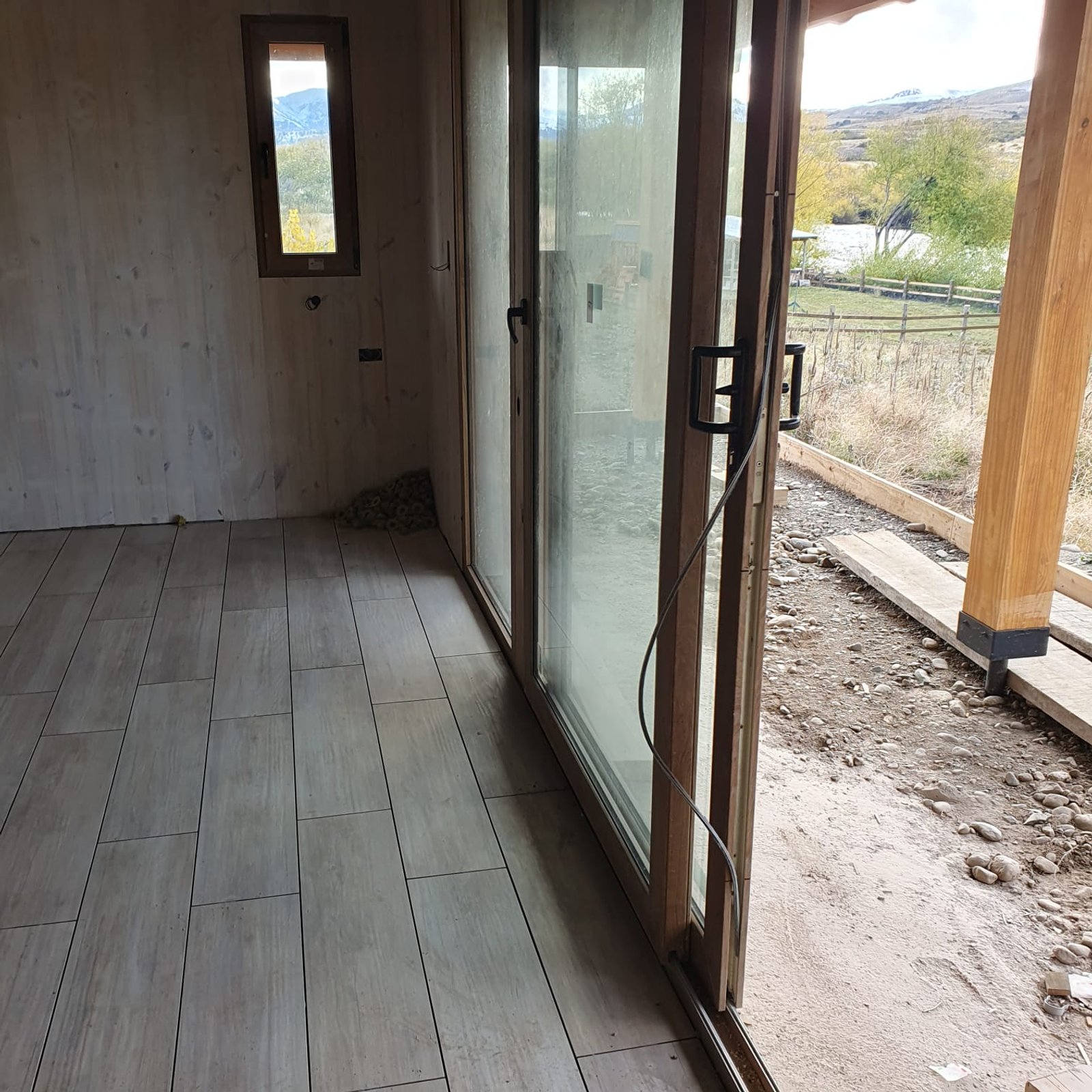 pasillo moderno con puertas de vidrio de piso a techo — proyecto Vivienda a orillas del Río Quilquihue, por TROKEN, en Neuquén