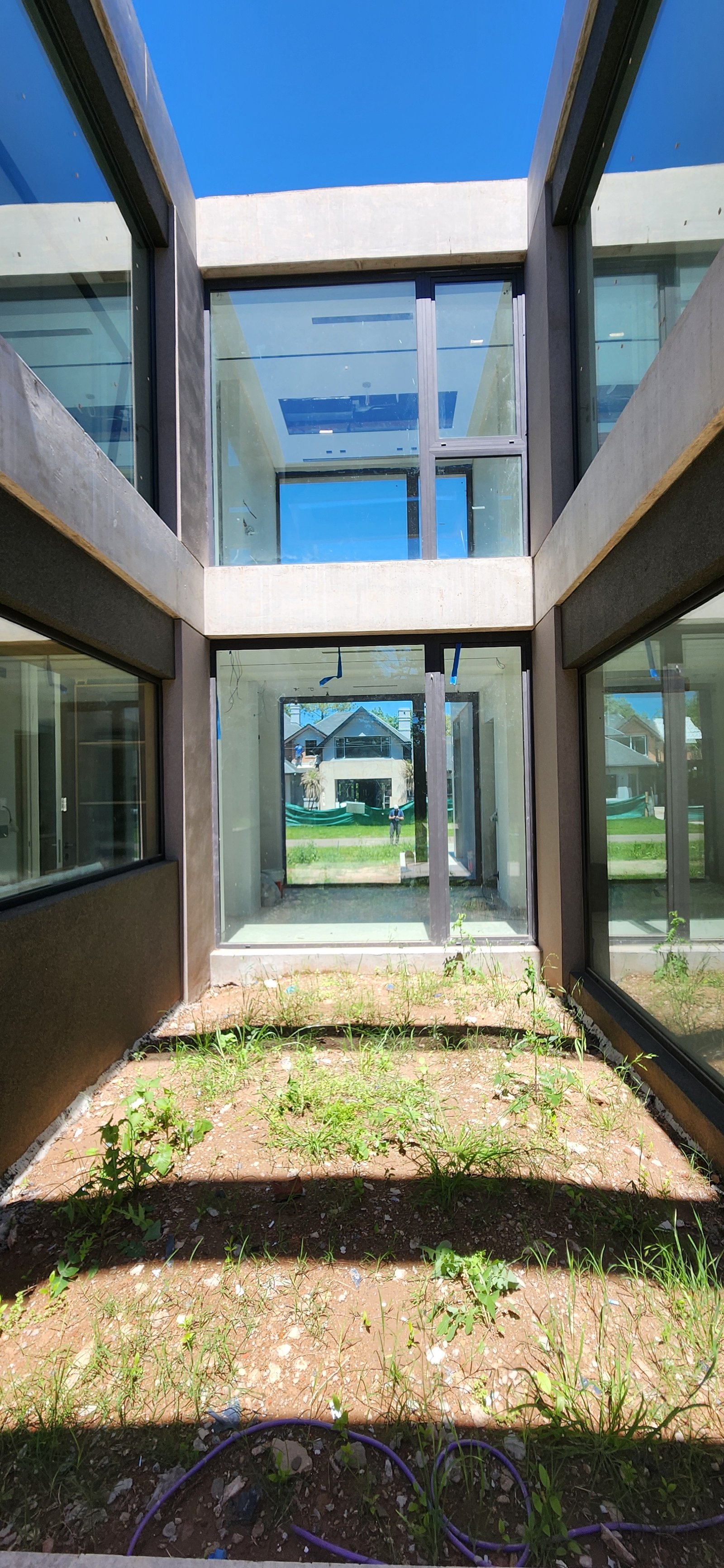 Fachada de casa moderna en construcción, con grandes ventanales y hormigón — proyecto Casa CAD, por Estudio Rifahi, en Moreno