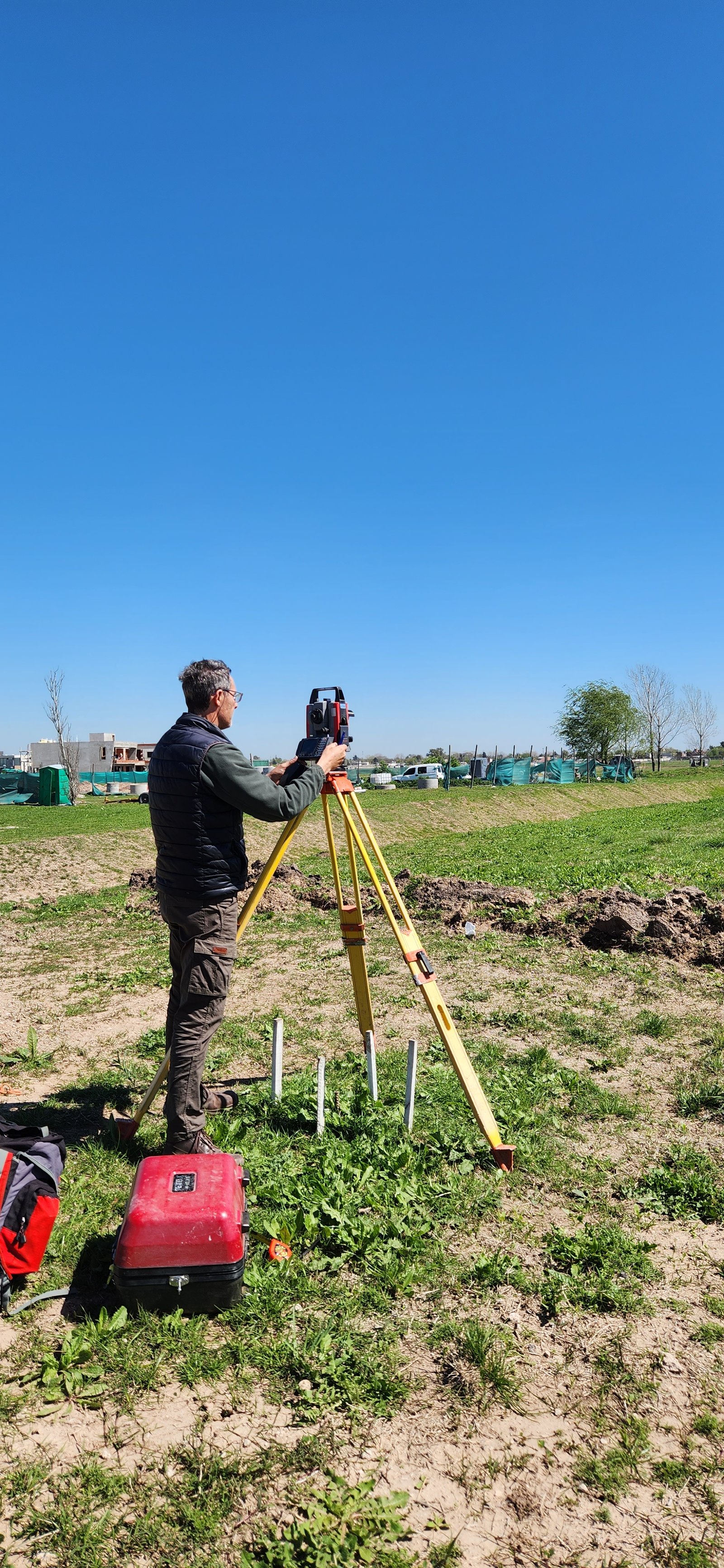 topógrafo trabajando en obra con equipo de topografía — proyecto Central Park - Terralagos, por Estudio Rifahi, en Canning