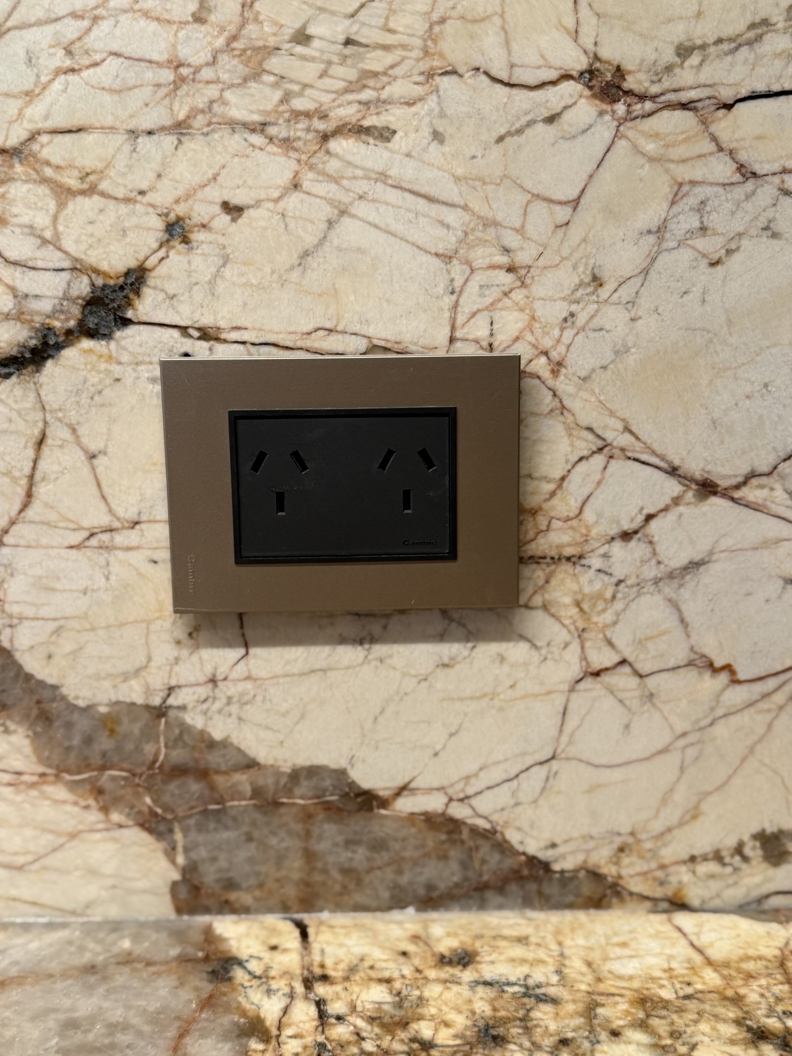 toma de corriente doble en pared de mármol con marco metálico — proyecto Casa Nativa, por Cambre, en B1648 Tigre
