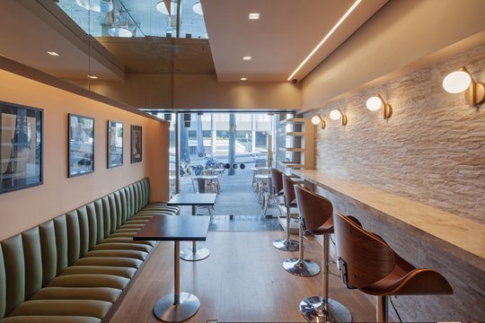 Cafe moderno con bancos verdes, pared texturada y claraboya — proyecto VELO VILLE CAFÉ, por Frederico Bicalho Arquitetura