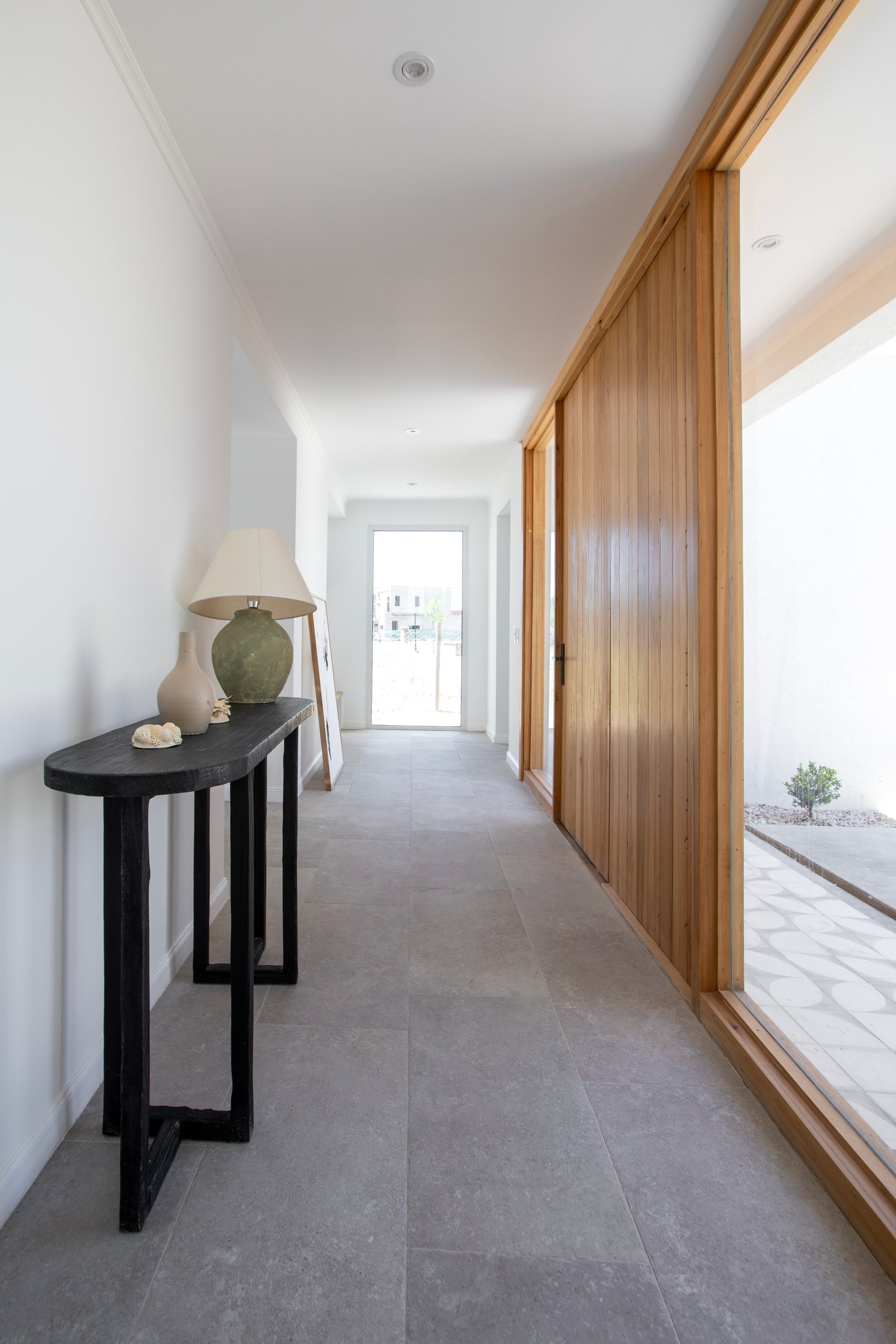 Pasillo moderno con revestimiento de madera y consola negra — proyecto OBRA LE PIETRE DEL CASALE SABBIA, por ILVA, en Provincia de Buenos Aires