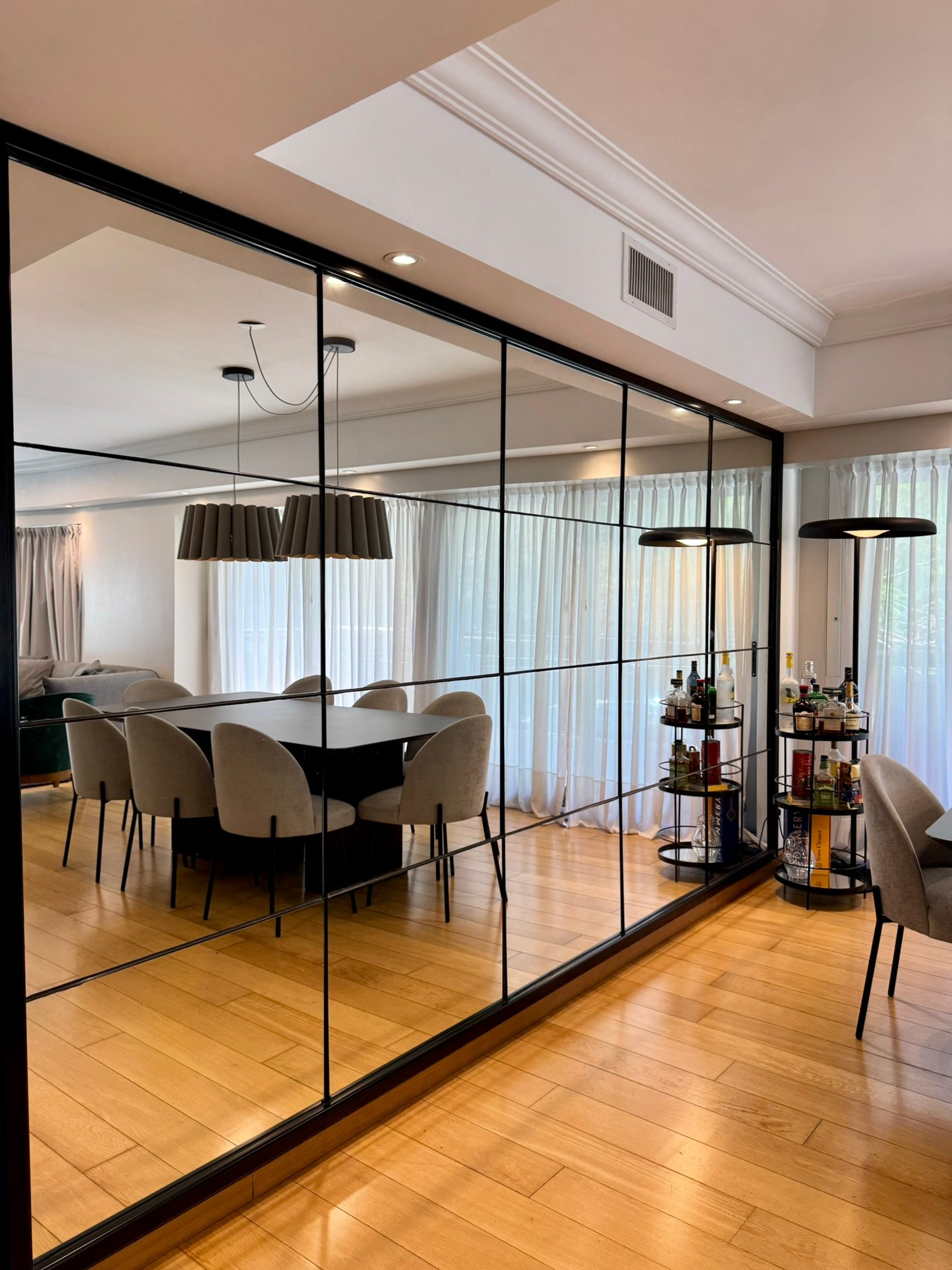 Comedor moderno con paredes espejadas, mesa negra y sillas beige — proyecto Olleros, por MDBK Arquitectura, en Belgrano