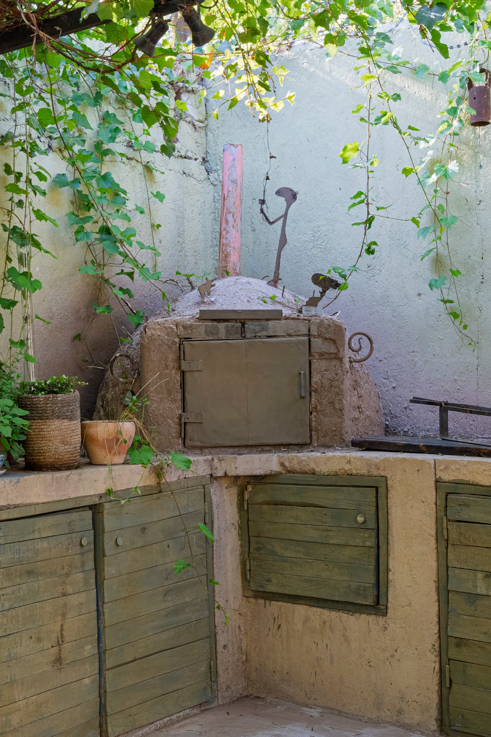 forno de pizza rústico com vegetação exuberante e armários verdes — projeto En el Taller, por Cristóbal Peña y Lillo, em Mendoza