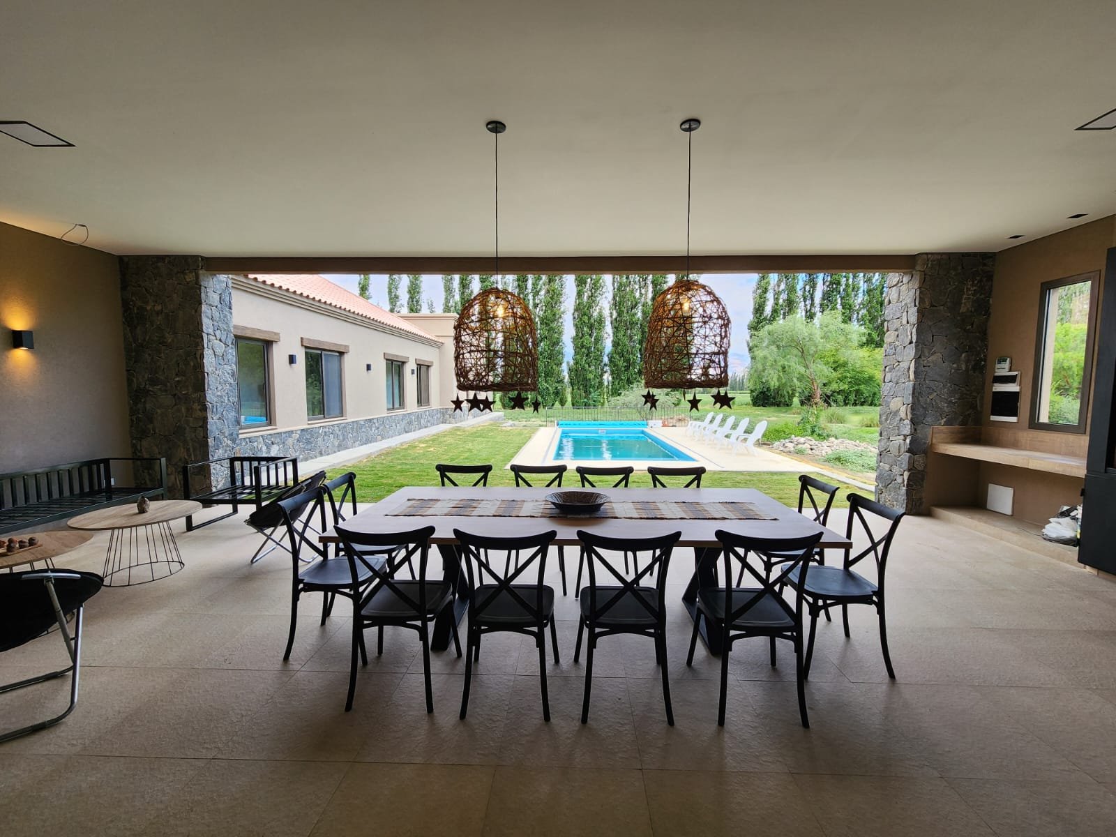 Comedor semi-exterior moderno con vista a la piscina — proyecto Ca La Estancia, por Luciana González Anderson, en Cafayate