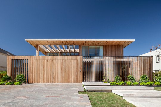 Fachada de casa moderna con revestimiento de madera y grandes ventanales — proyecto Casa JIB, por MUCHTEK, en Nordelta