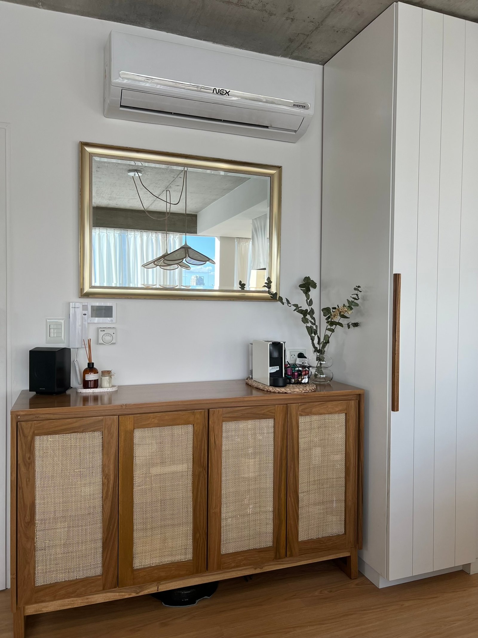 Mueble de madera con puertas de caña, espejo dorado y techo de hormigón — proyecto Velasco, por MDBK Arquitectura, en Villa Crespo