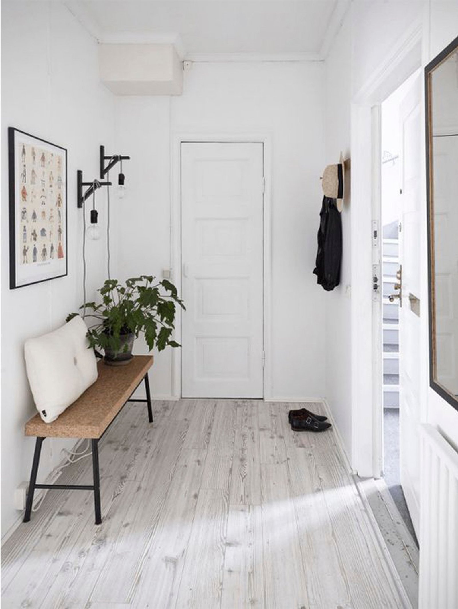 Pasillo escandinavo minimalista con banco, planta y cuadros — proyecto Pisos Vinílicos, por The Flooring Company