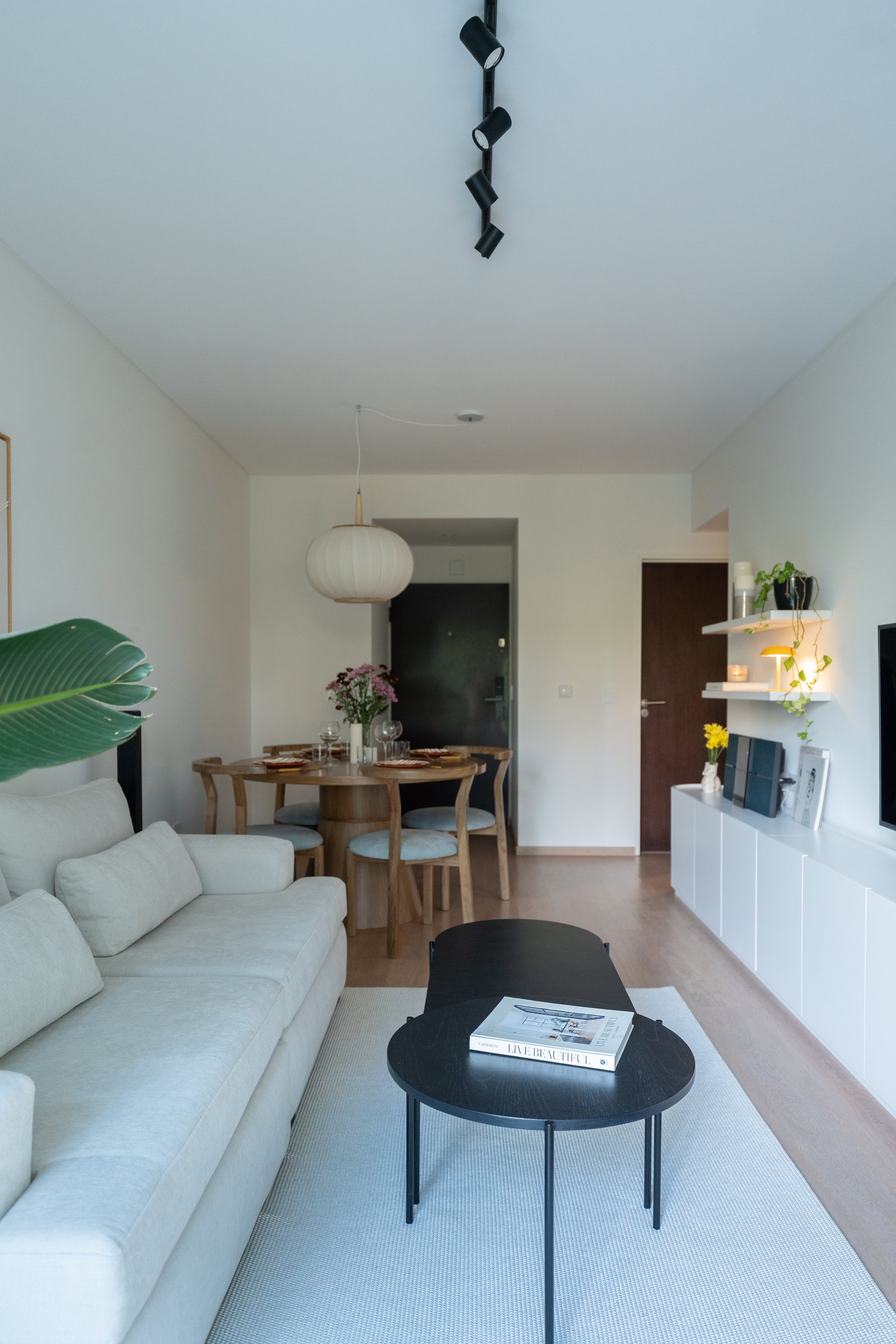 Sala moderna escandinava con sofá blanco, mesa de piano y comedor — proyecto Ugarte, por Estudio BDM, en Cdad. Autónoma de Buenos Aires