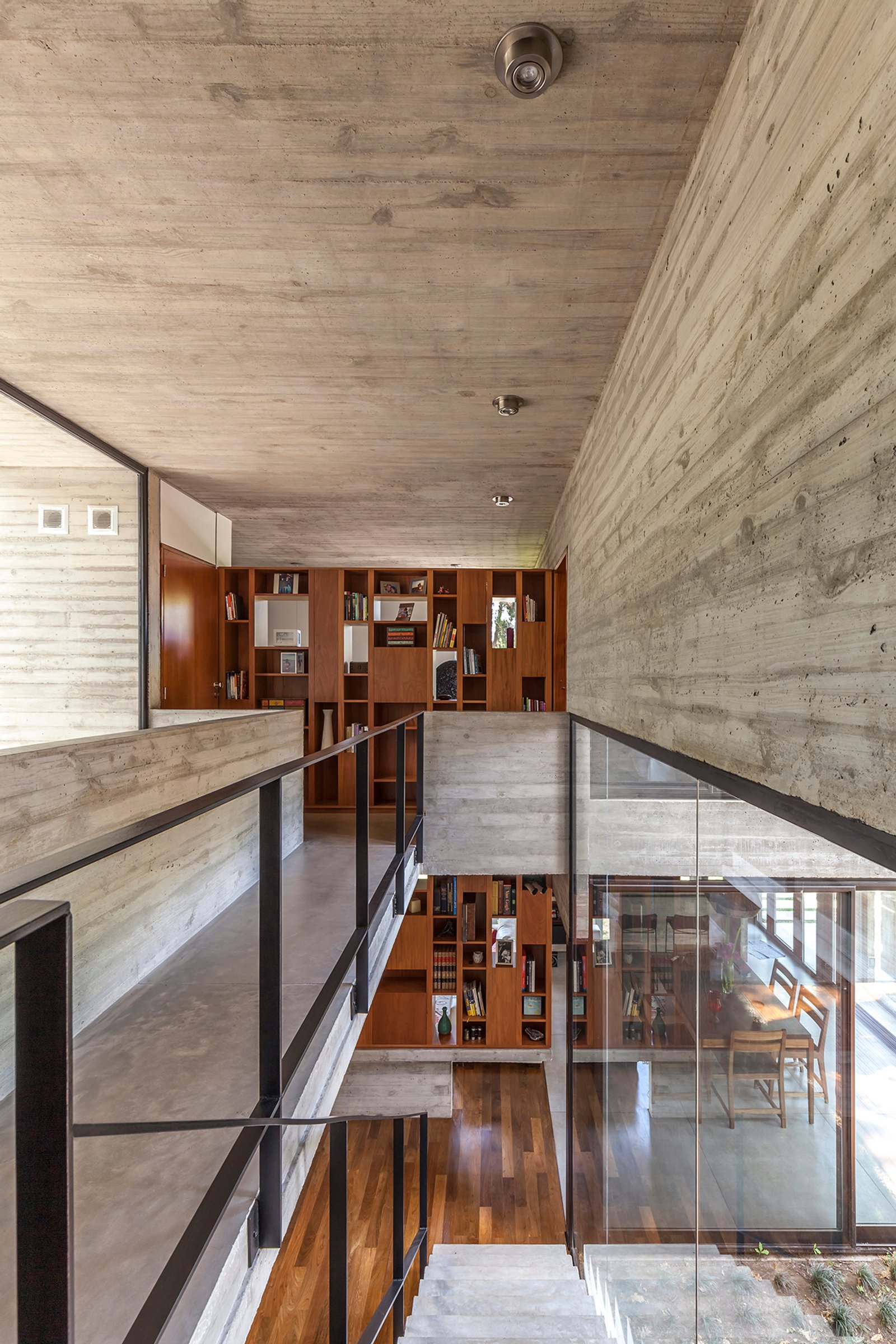Espacio moderno de hormigón expuesto con estanterías de madera integradas — proyecto Casa Aranzazu, por Besonías Almeida arquitectos, en B1667 Tortuguitas