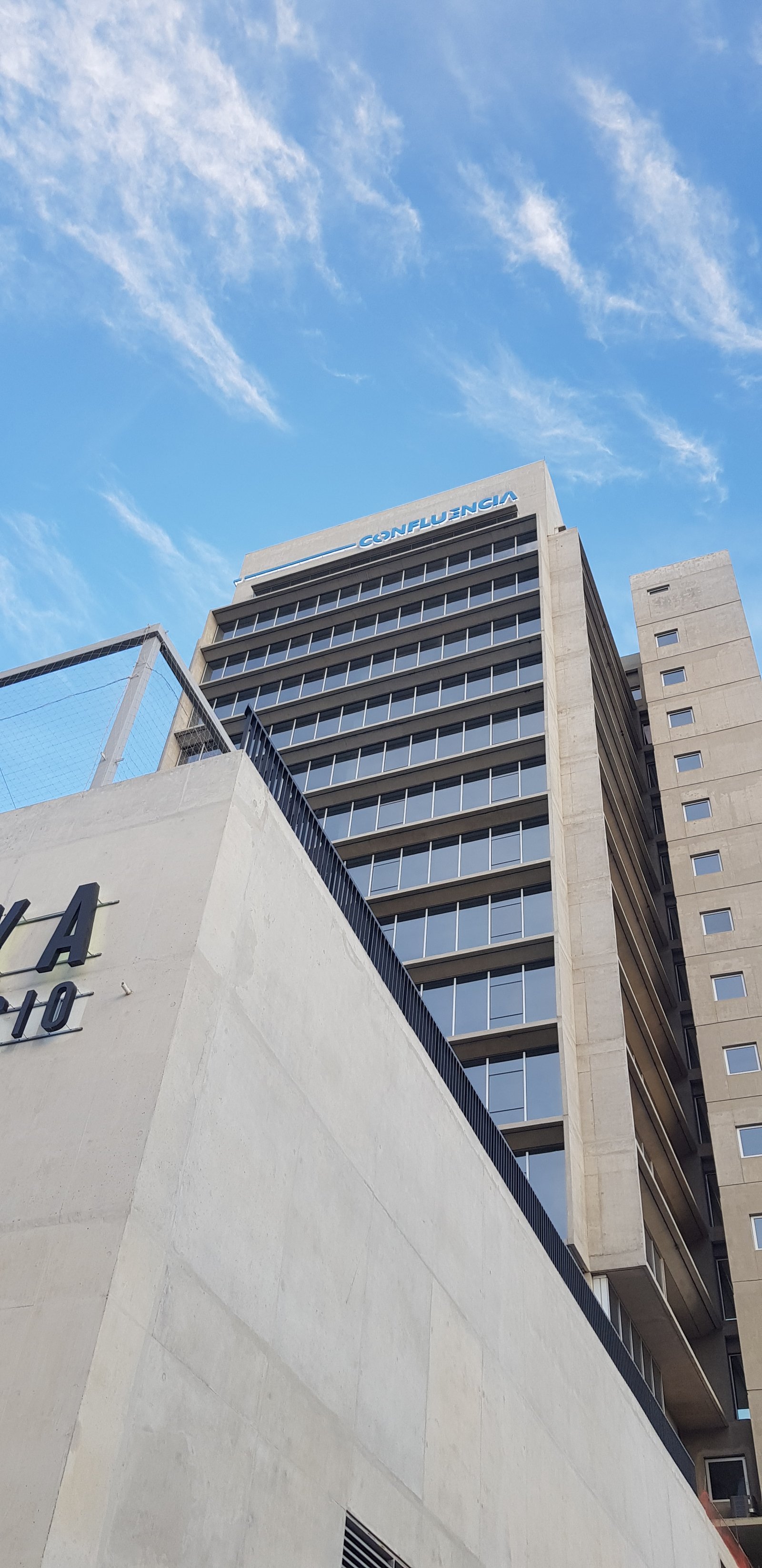 Edificio moderno de hormigón con ventanales amplios y cielo nublado — proyecto TORRE CONFLUENCIA GYM HOKA, por Arquitecto Germán Müller, en Av. Dr. Ramón 748
