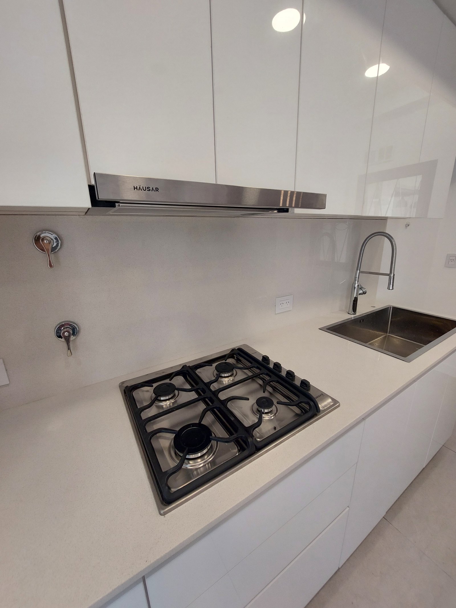Cocina moderna con gabinetes blancos brillantes y mesada de piedra clara — proyecto MISTRAL, por Arquitecta, en Villa Pueyrredón