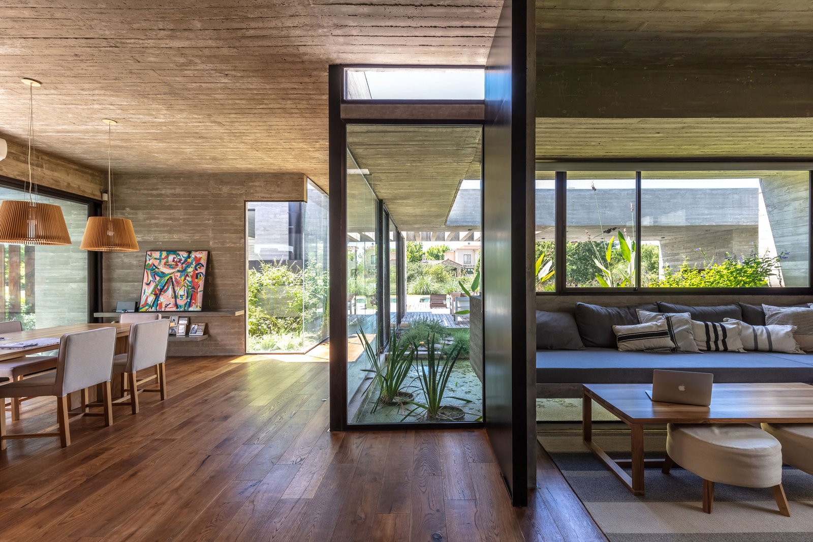 Living moderno con hormigón visto y ventanales amplios al exterior — proyecto Casa Pilará, por Besonías Almeida arquitectos, en Pilar