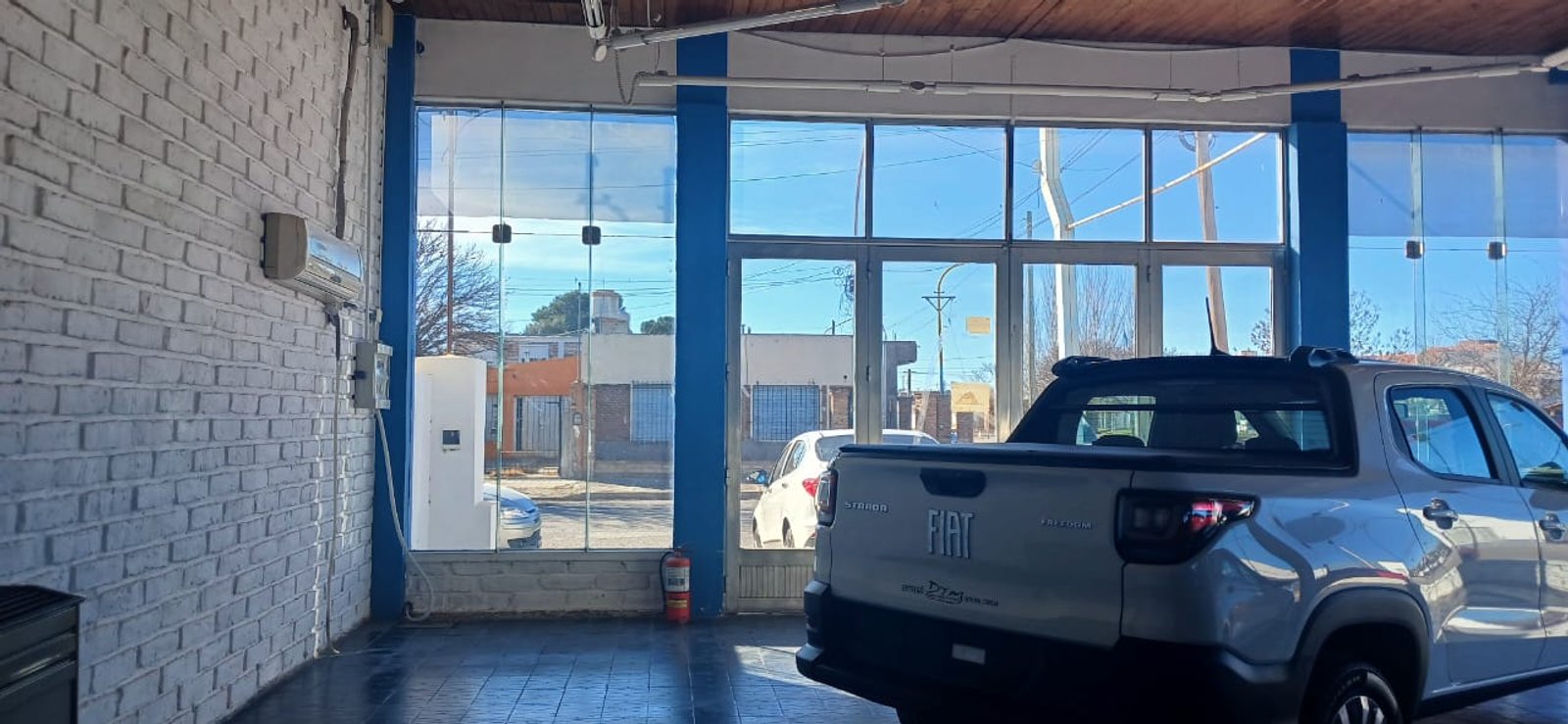 Interior de concesionario con auto pickup y pared de ladrillo — proyecto AGENCIA DTM, por Amorosi Espacios de Diseño, en Gral. Conesa