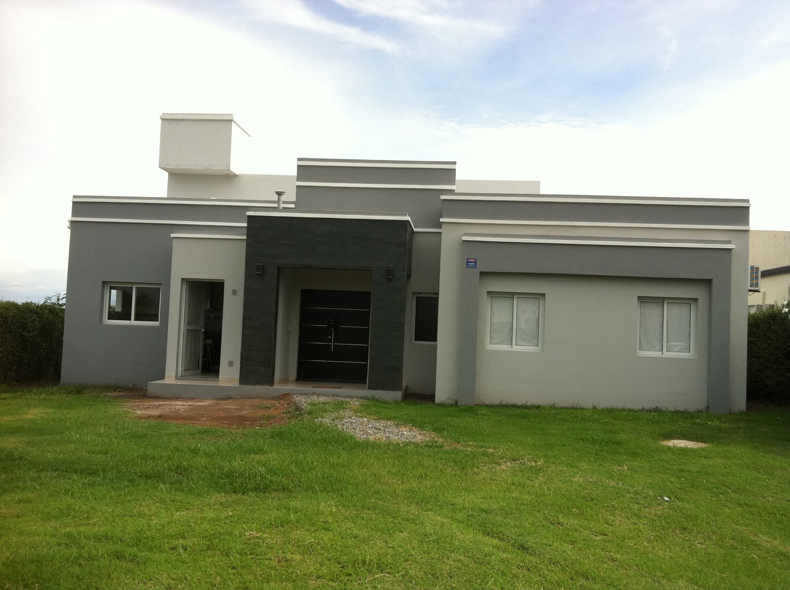 Fachada de casa moderna cinza e preta com jardim — projeto CASA DUARTE, por HORACIO MEJAIL, em Cno. de Sirga 1452