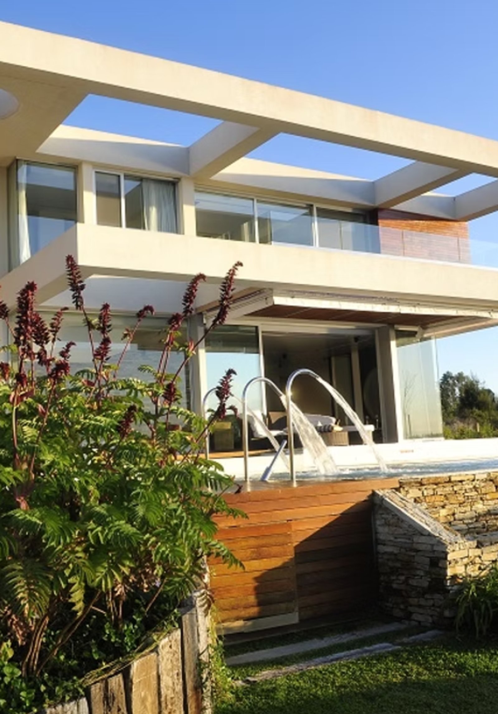 Piscina moderna con deck de madera y cascada en casa minimalista — proyecto Casa Cinta, por Barrionuevo Arquitects, en B2814 Los Cardales