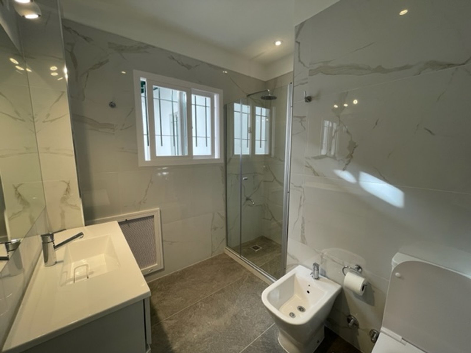 Baño moderno con paredes de mármol y ducha amplia — proyecto Diaz Velez , por Estudio NET Arquitectura , en Díaz Vélez 1140