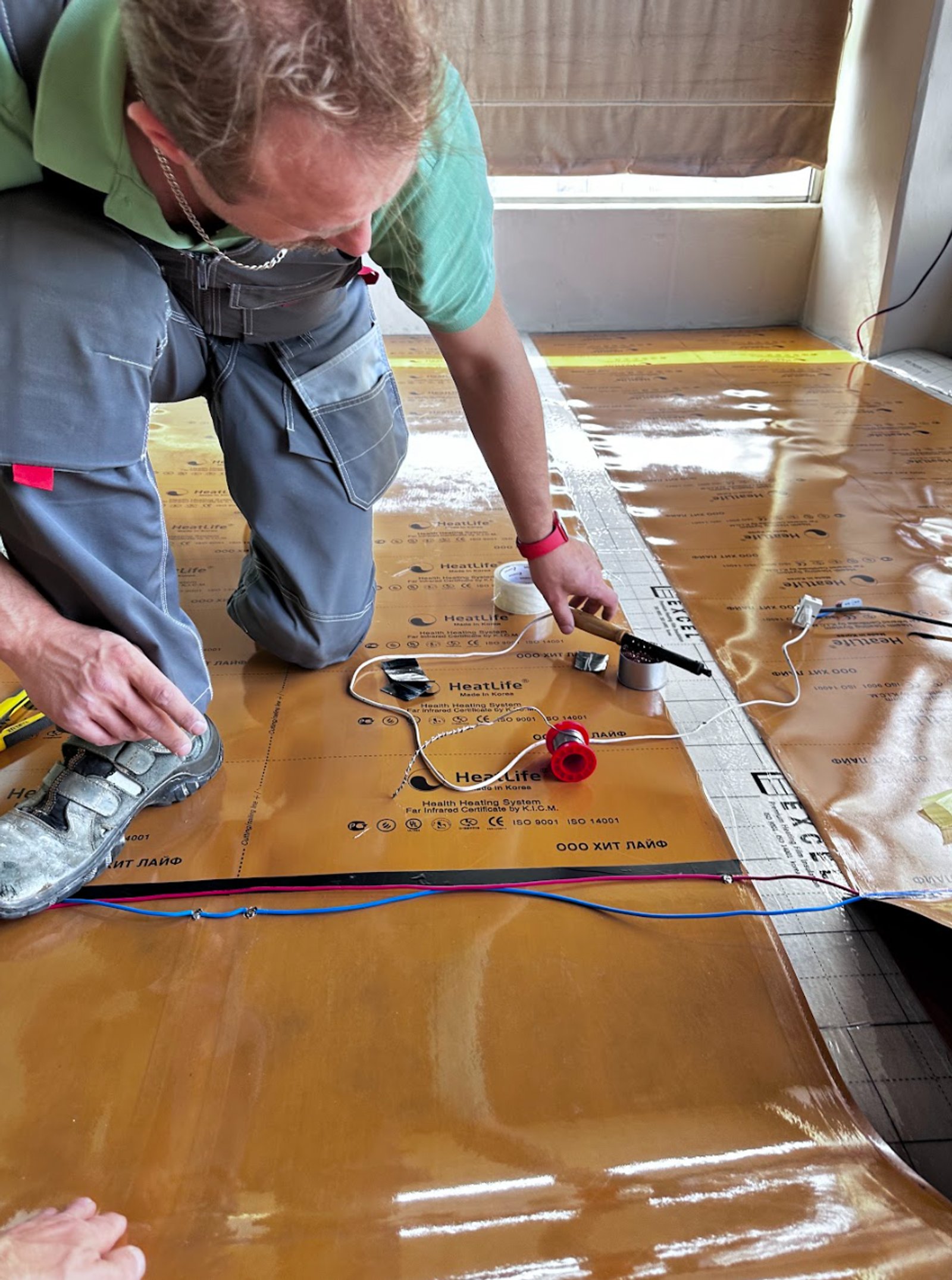 Homem instalando piso aquecido elétrico em obra — projeto Balcón, por HEAT LIFE