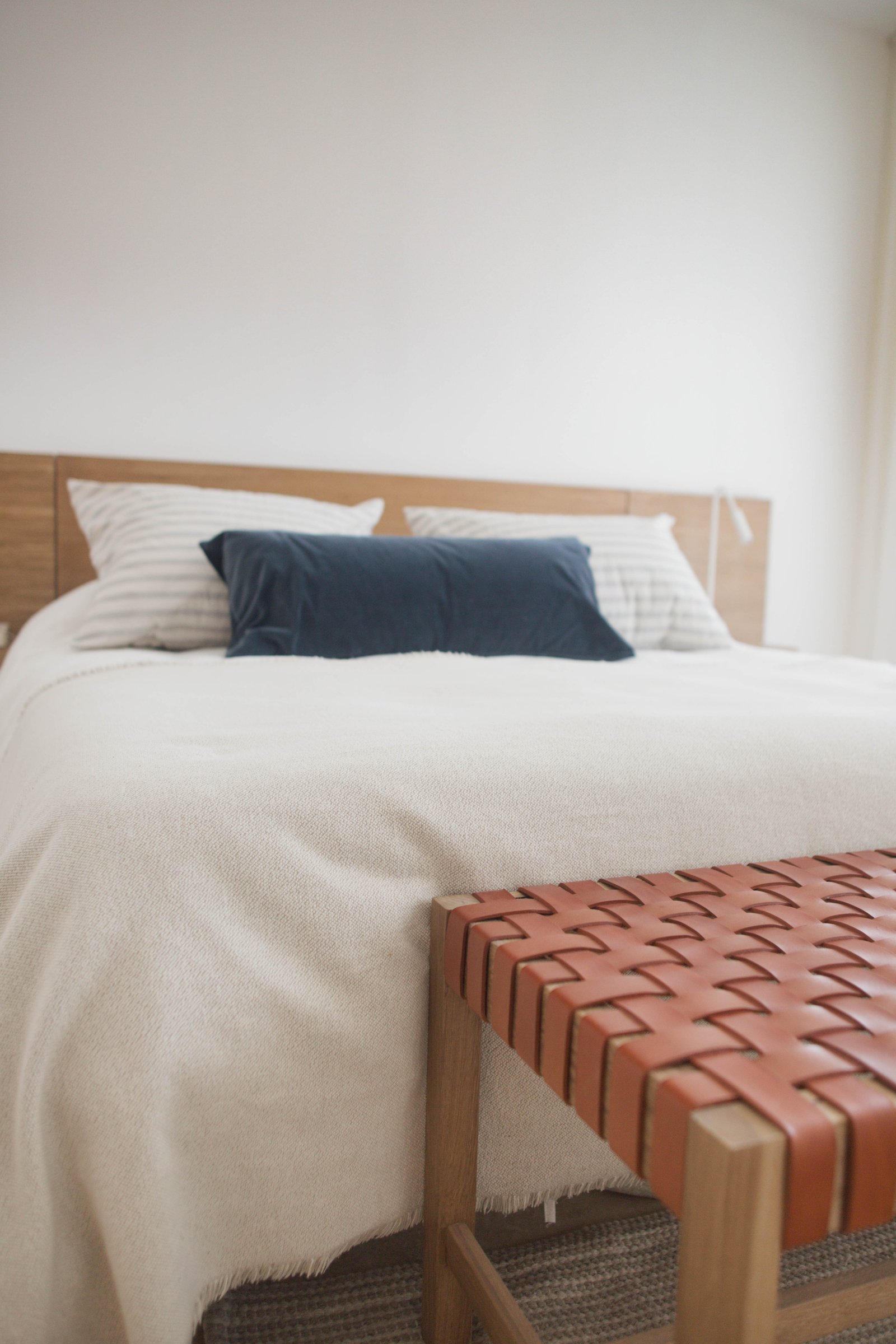 Dormitorio minimalista con cama doble, banco de cuero tejido y luz indirecta — proyecto Urbana las lomas, por LACROZE DESIGN STUDIO, en San Isidro