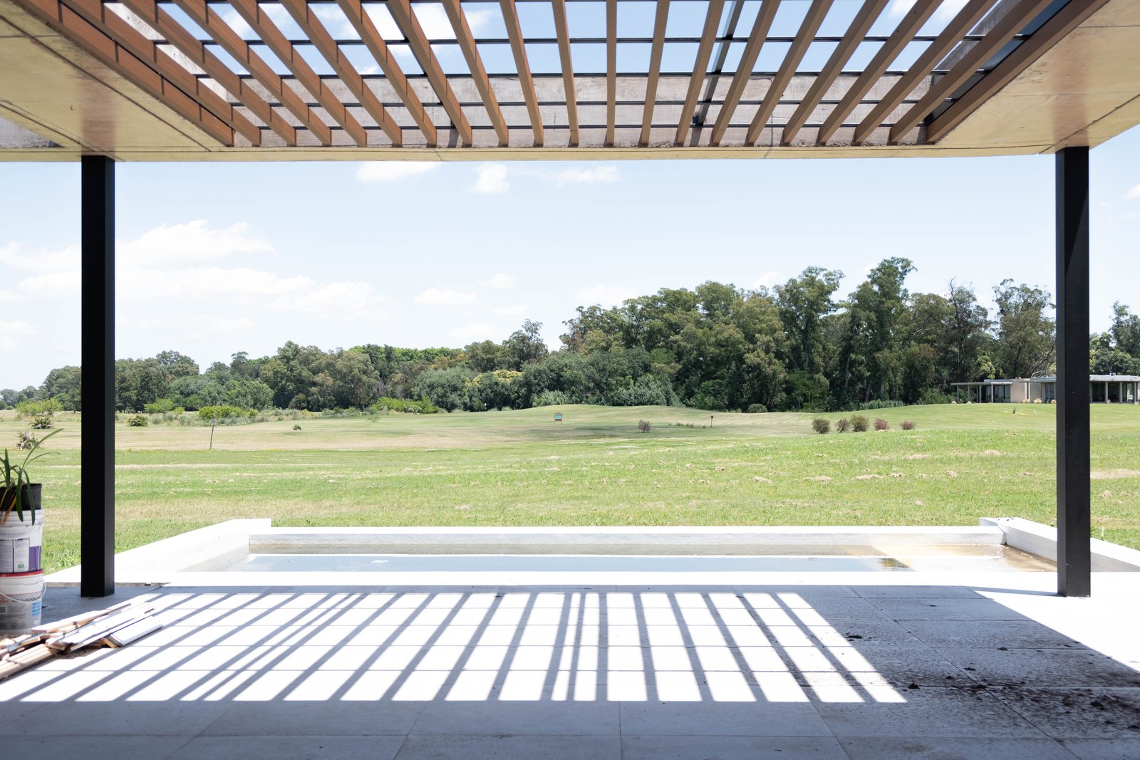 Piscina moderna rodeada de césped y pérgola de madera — proyecto CASA GOLF, por SEDE Arq., en Av. Pereda S/N