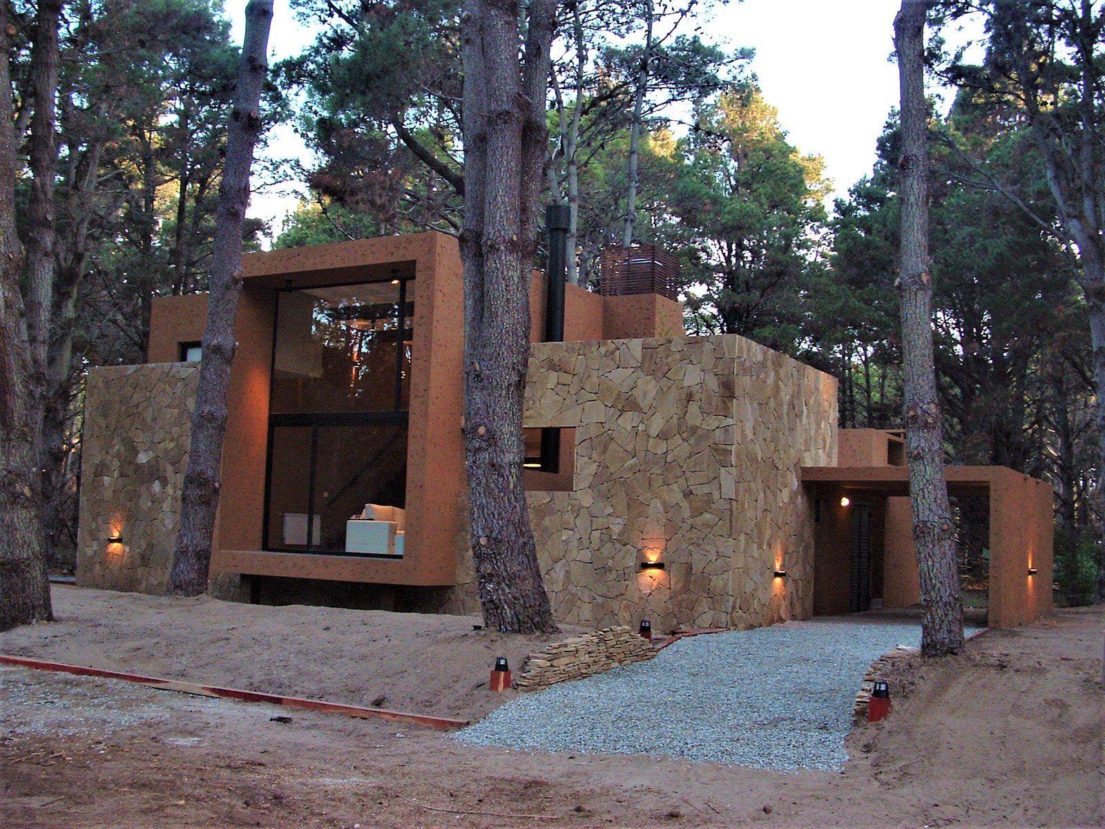 fachada moderna de piedra y hormigón en bosque — proyecto LA  ALHAMBRA, por GJF estudio, en Costa del Este