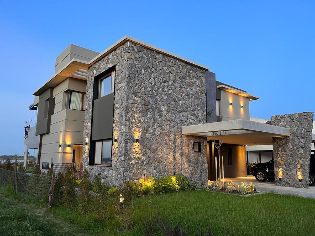 Fachada moderna de casa com detalhes em pedra e concreto — projeto Puertos del Lago - Muelles, por CM Espacio & Arquitectura, em Belén de Escobar