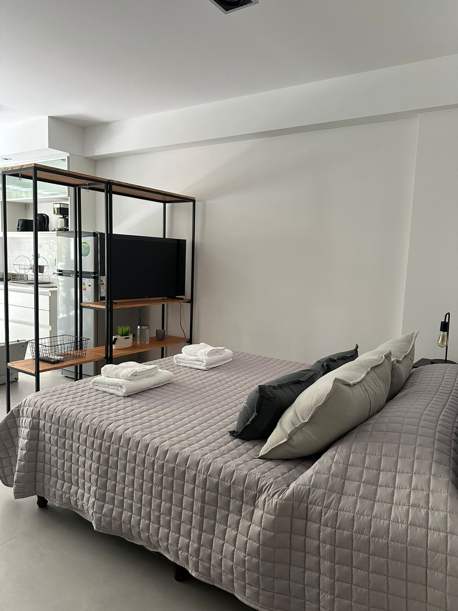 Quarto moderno com cama, prateleira de metal e TV — projeto Airbnb, por Estudio Hirsch, em Buenos Aires