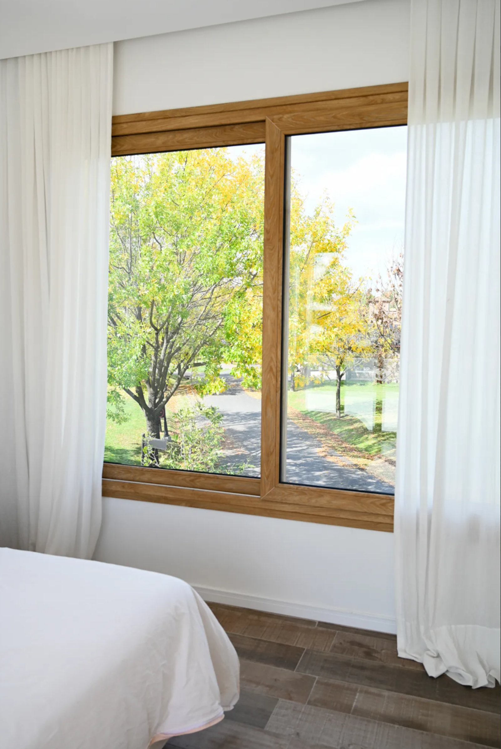 Dormitorio minimalista con gran ventana al jardín otoñal — proyecto Diseño mediterráneo, alma luminosa, por ATRIM GLOBAL, en Bella Vista