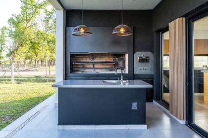 Quincho moderno con isla de cocina y parrilla integrada — proyecto Casa ALM57, por EZ architects, en Canning