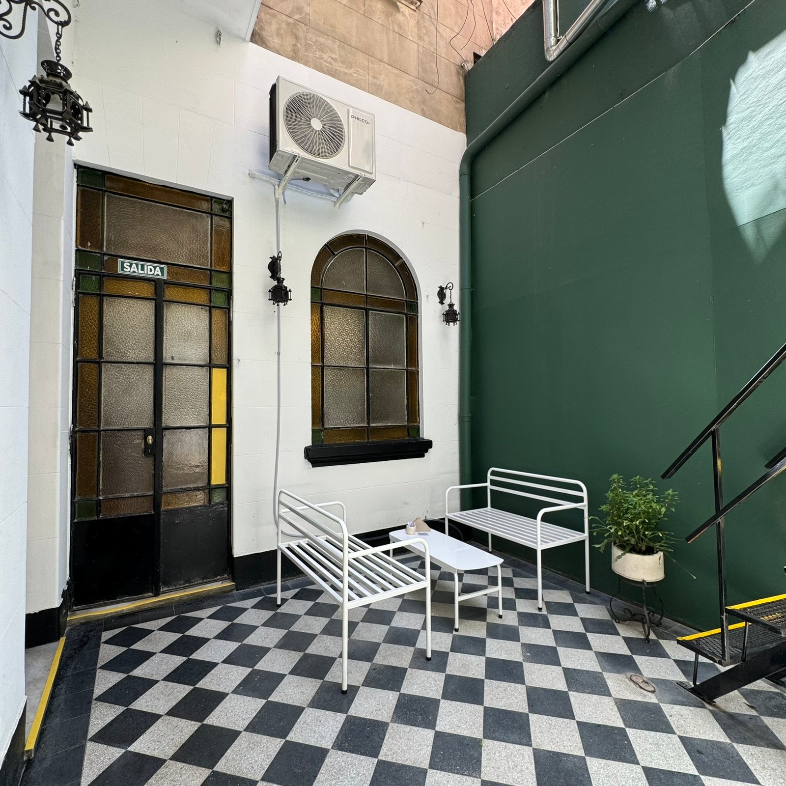 Pátio moderno com piso xadrez e parede verde — projeto UGA Coffee House, por MDBK Arquitectura, em Almagro