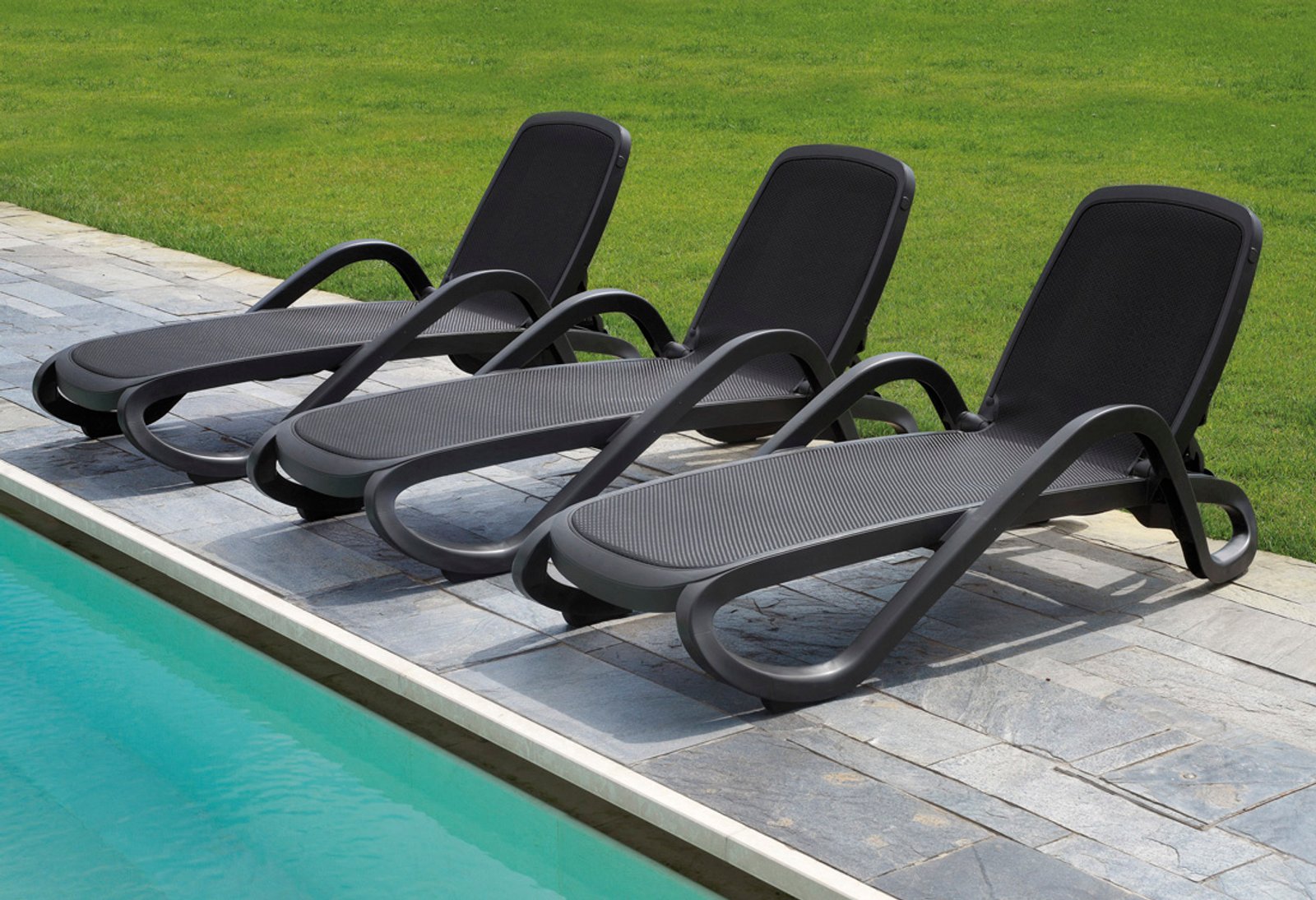 cadeiras espreguiçadeiras pretas plásticas na área da piscina — projeto Reposeras NARDI®, por Casa Nuñez