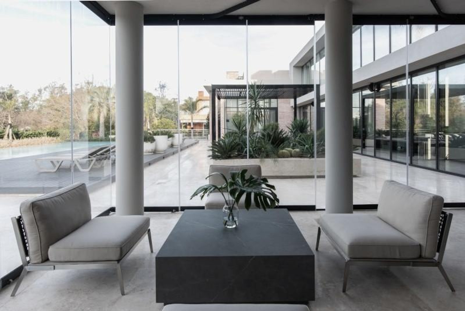 Espacio de estar interior-exterior con vista a jardín y mobiliario gris — proyecto Espacios, por BURANI, en Martínez