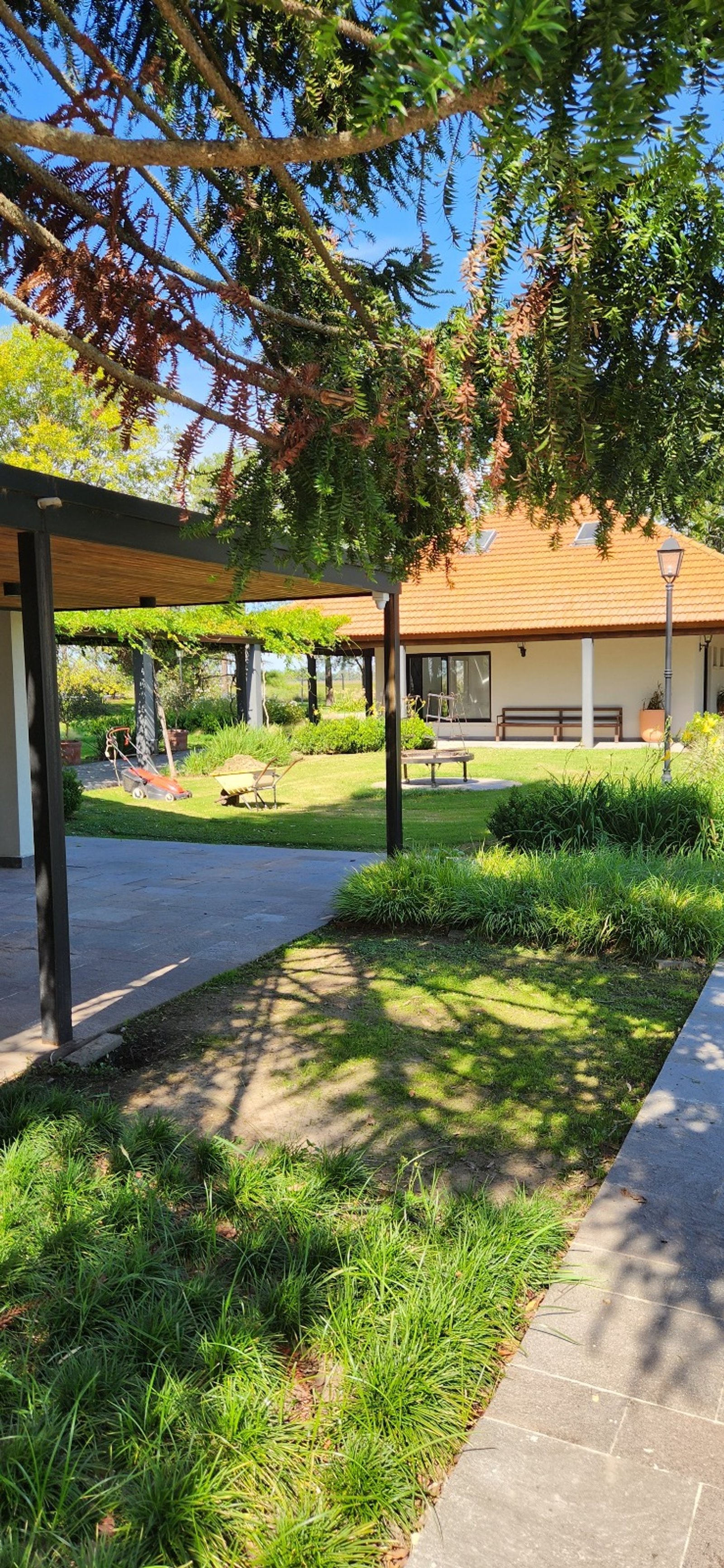 Jardín y galería cubierta con casa de estilo moderno y rústico — proyecto Casa COAL, por Estudio Rifahi, en B2814 Los Cardales