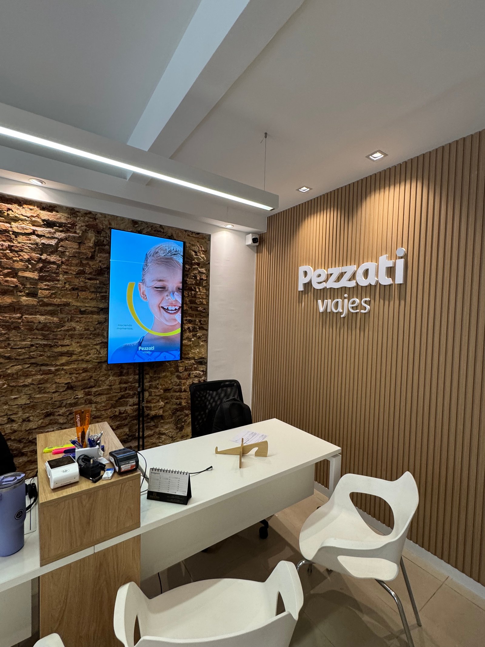 Oficina moderna con pared de madera y ladrillo visto — proyecto Pezzati viajes , por Remodela tu local , en Buenos Aires