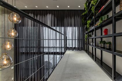 Pasillo industrial con escalera, plantas colgantes y lámparas cálidas — proyecto Duo Morumbi, por Pricila Dalzochio