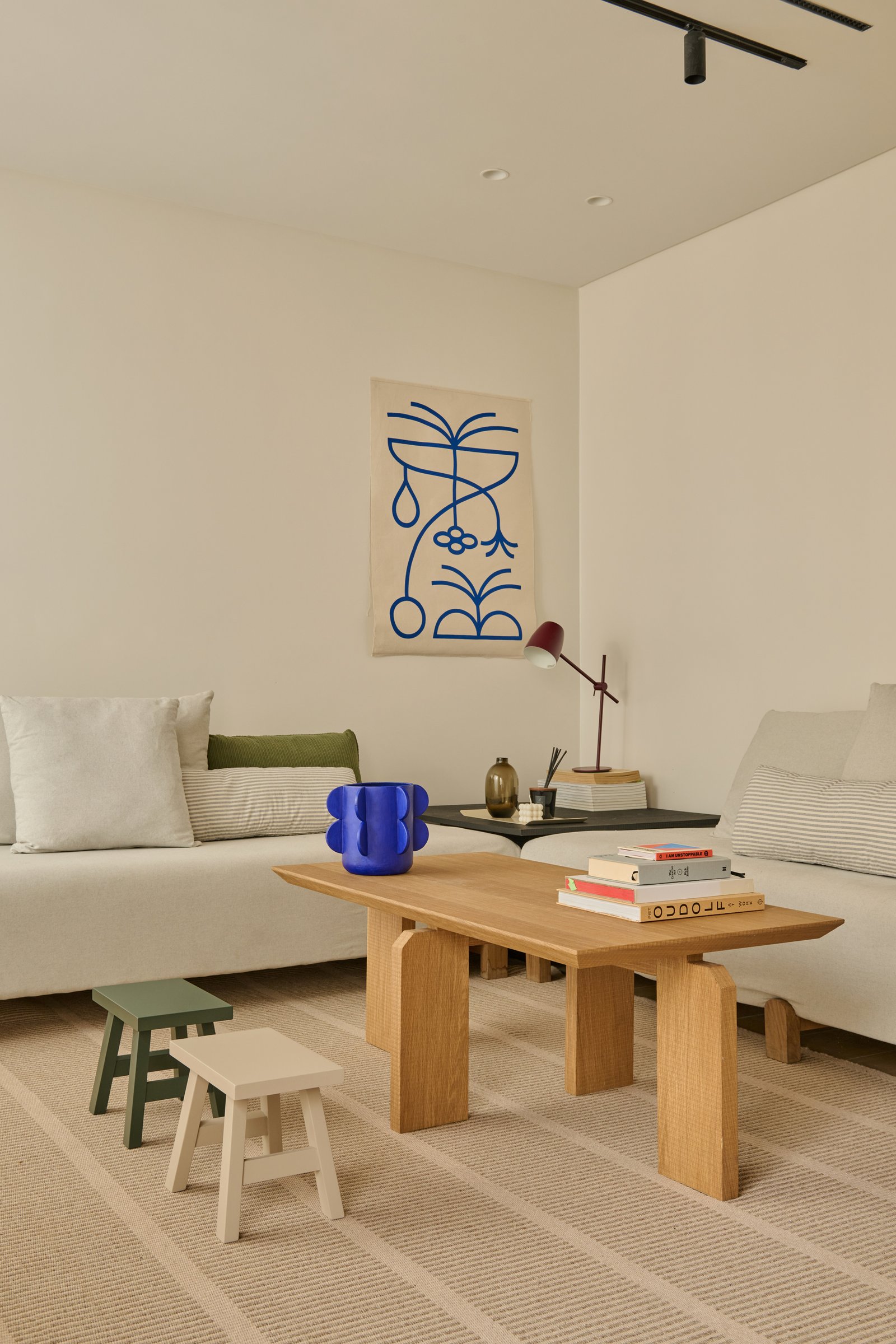 Living minimalista con sofá blanco, mesa de madera y arte abstracto — proyecto VIRREY AVILES, por loom, en Buenos Aires