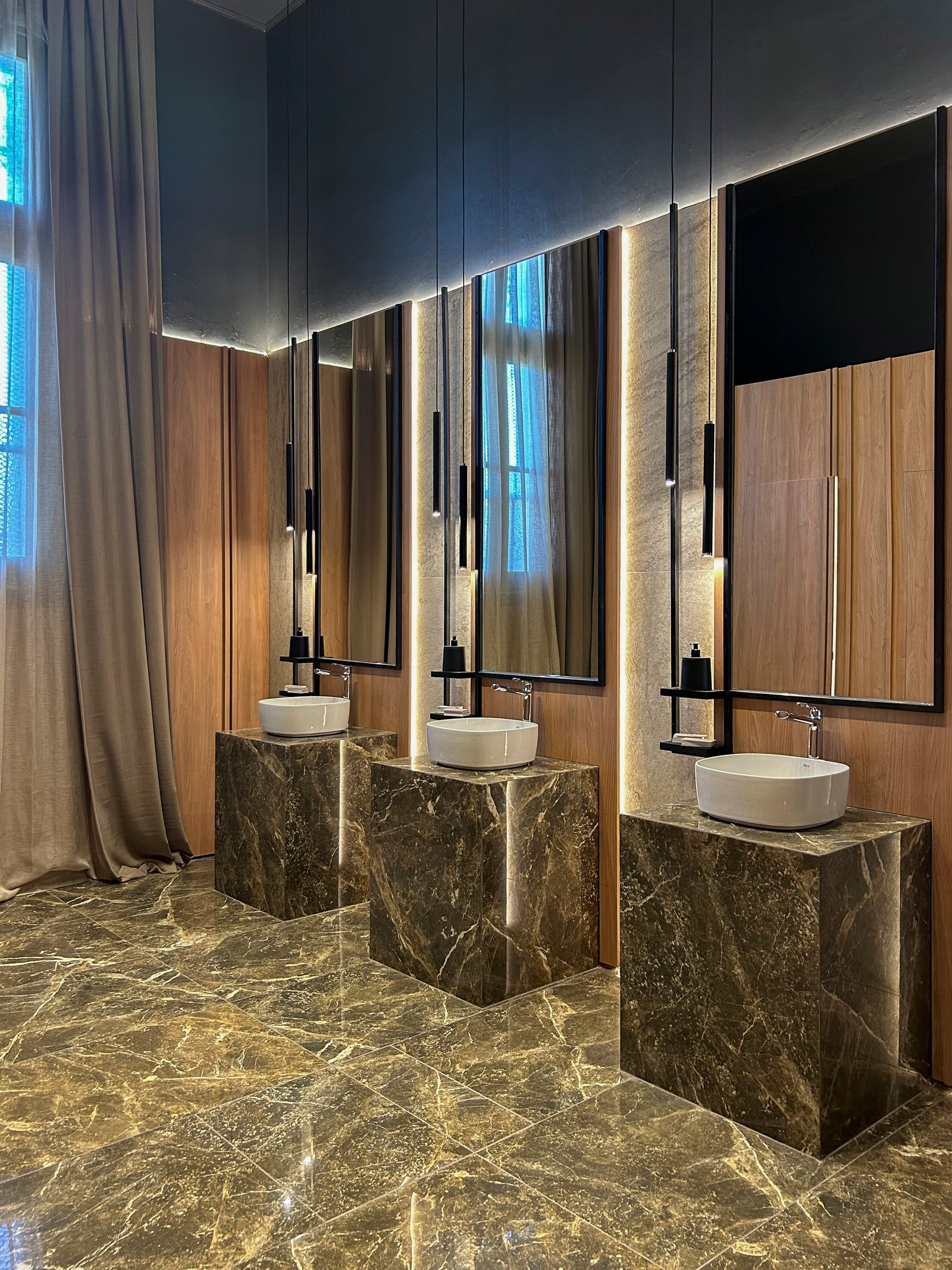 Baño moderno con vanitories de piedra, iluminación tenue y detalles de madera — proyecto Marmoles, por Vite Porcellanato