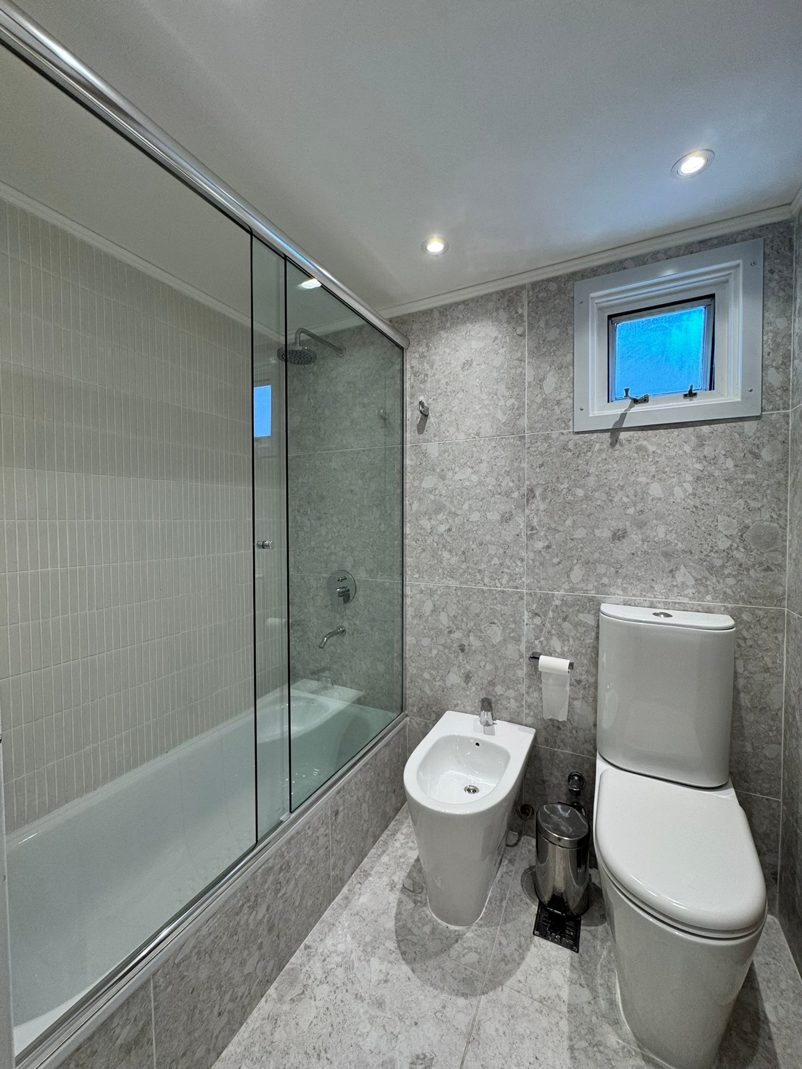 Baño moderno con bidet grande, bañera exenta y paredes de piedra — proyecto Lafinur, por MDBK Arquitectura, en Palermo
