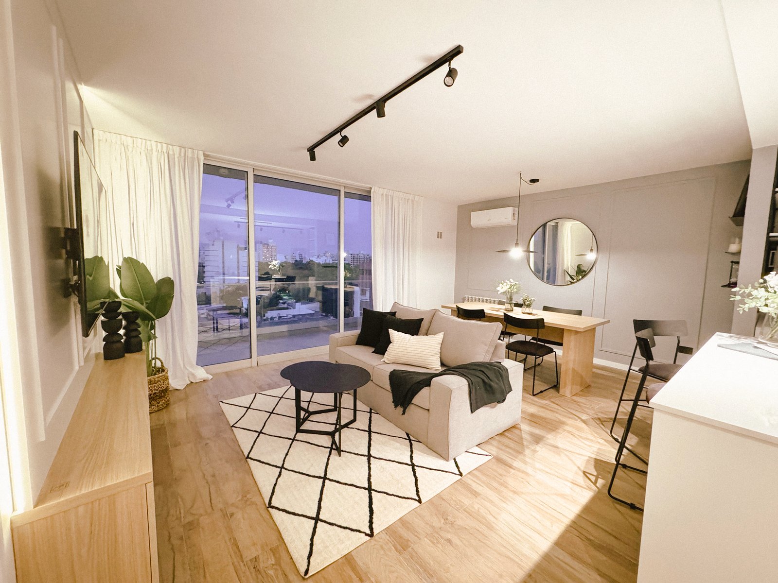 Living moderno con ventanales amplios y alfombra geométrica — proyecto Departamento Airbnb, por Jeitinho Estudió Creativo, en La Plata