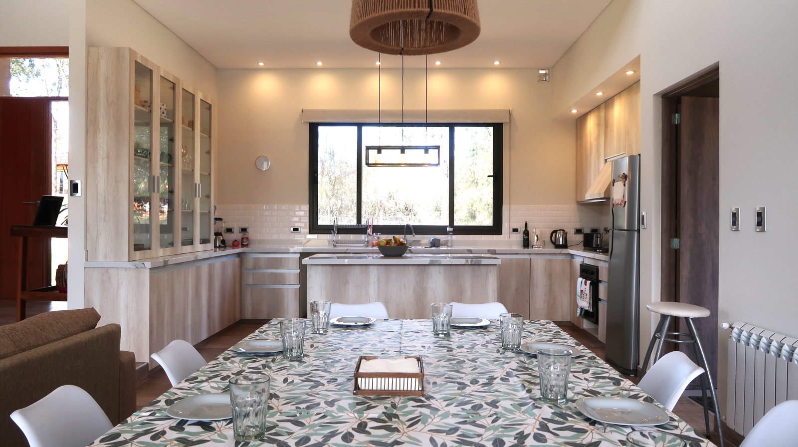 Comedor moderno con mesa de madera, sillas y lámpara tejida — proyecto Casa La Paz, por Luciana González Anderson, en Salta