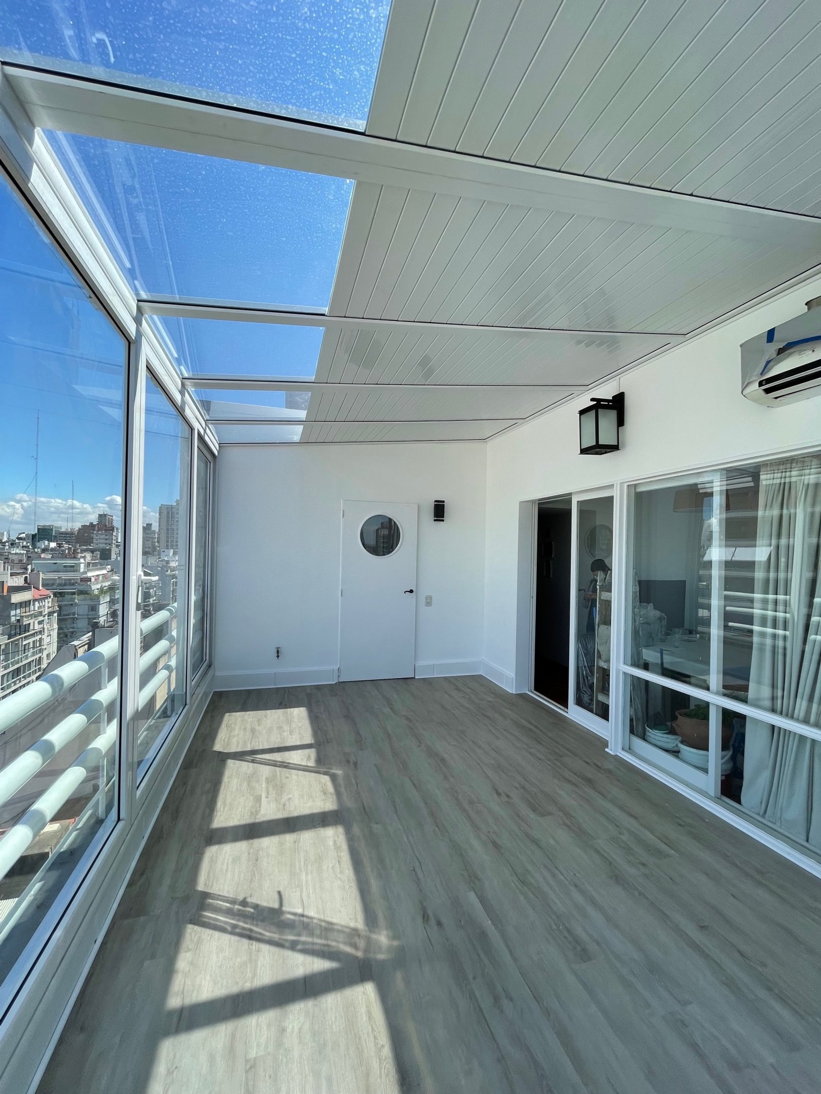 Terraza moderna con techo de vidrio y vista urbana — proyecto Peña, por Estudio NET Arquitectura , en Peña 2726
