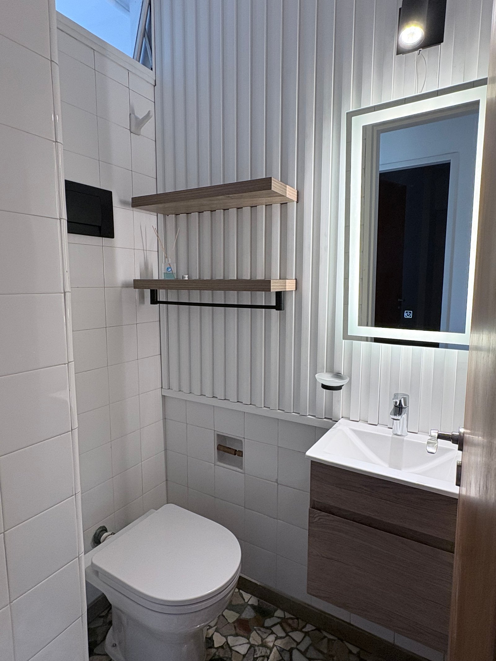 Baño moderno con lavabo sobre mueble de madera y espejo retroiluminado — proyecto Proyecto America, por LF arquitecta, en Av. 7 & C. 50