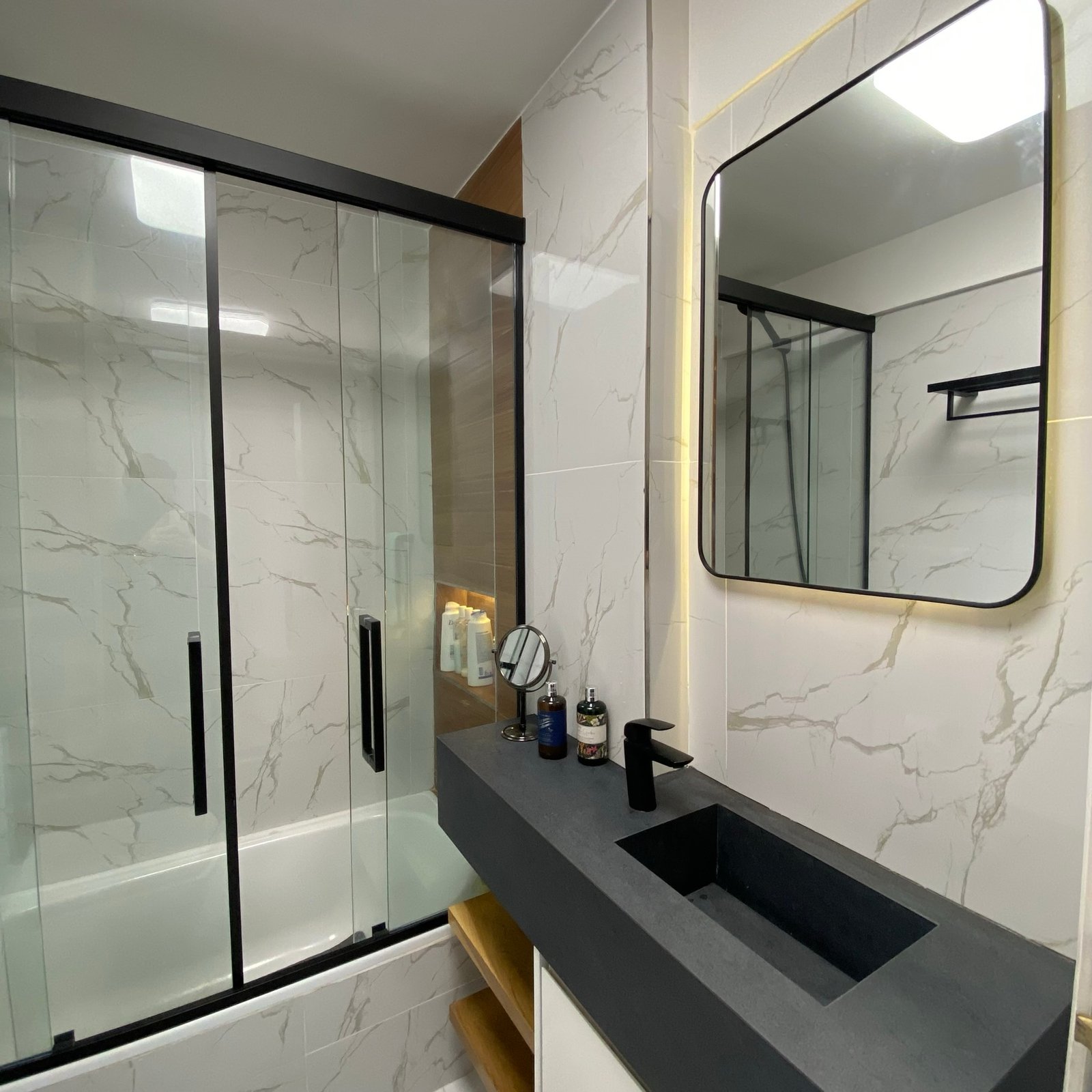 Baño moderno con paredes de mármol, ducha vidriada y vanitory de concreto — proyecto Pringles, por MDBK Arquitectura, en Almagro