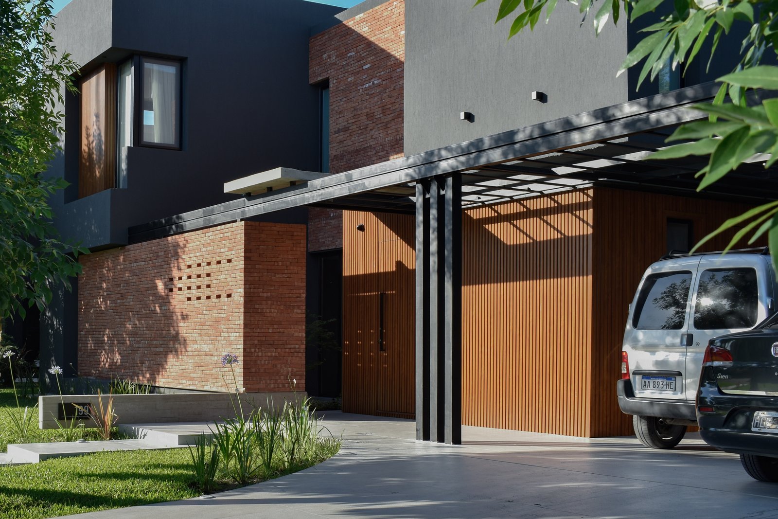 Fachada moderna con hormigón, madera y grandes ventanales — proyecto CASA HC, por Daniel Daniele - Oficina de Arquitectura, en Canning
