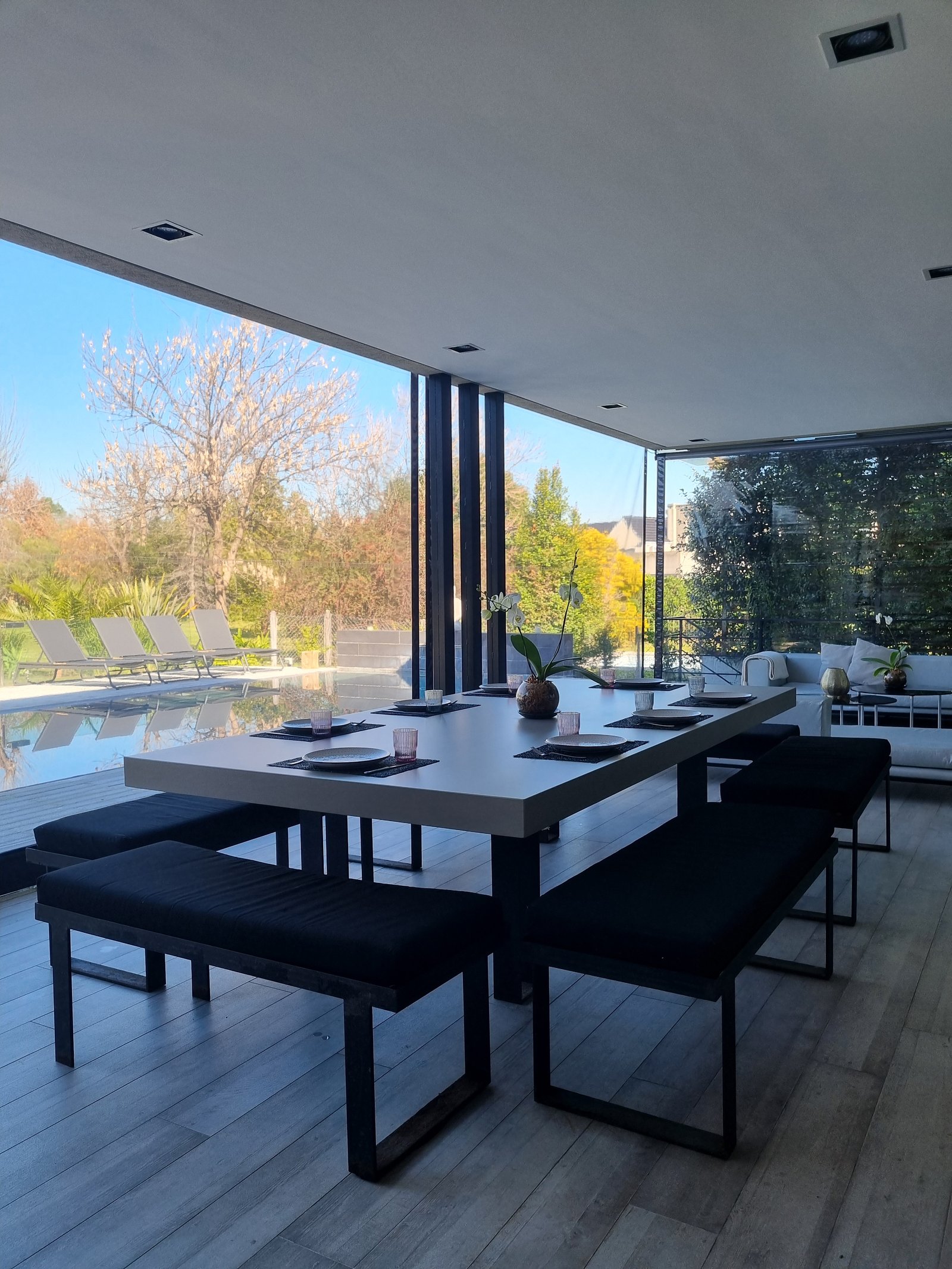 Sala de jantar moderna semi-externa com vista para a piscina — projeto Toldos Verticales, por ToldosYa