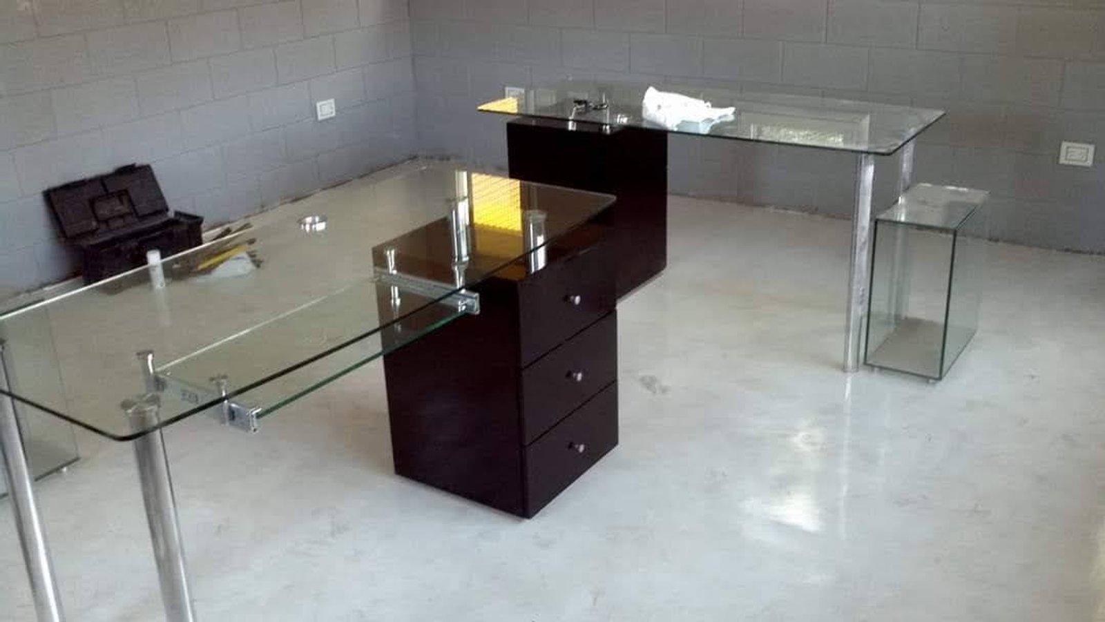 oficina moderna con escritorios de vidrio y paredes de concreto — proyecto Escritorios en vidrio con cajonera pegado laser uv , por Cristalcenter, en Nordelta