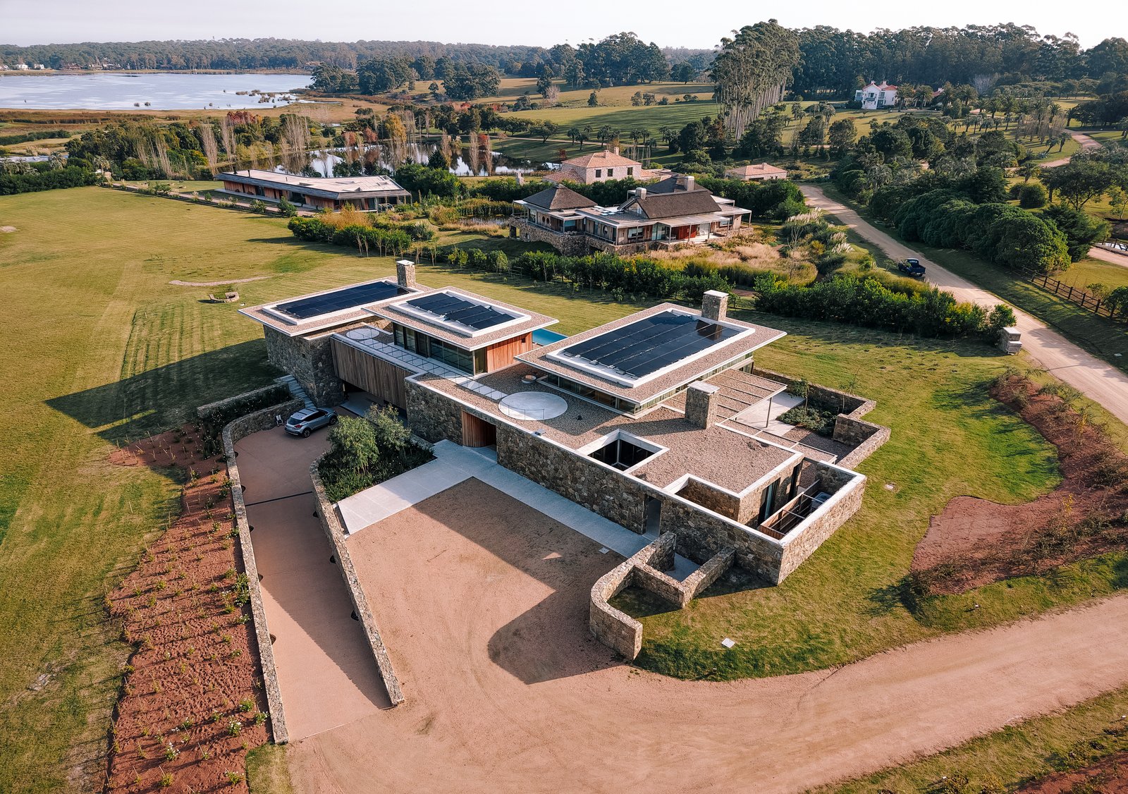 Casa moderna de concreto com grandes janelas e pátio — projeto Laguna Estates, em Maldonado