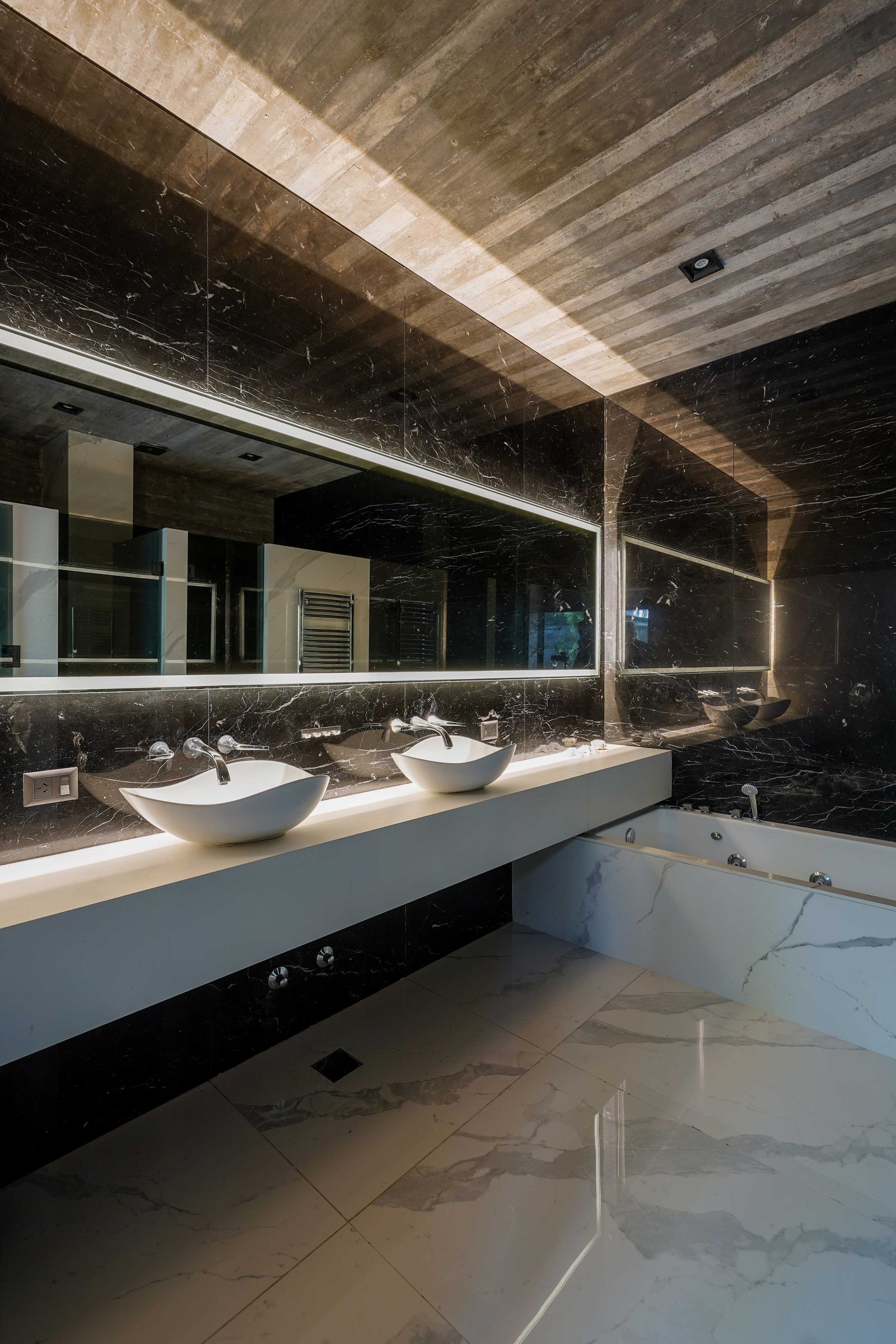 Baño moderno de lujo con mármol negro y techo de madera — proyecto Casa 4H, por Besonías Almeida arquitectos, en X6VF+67